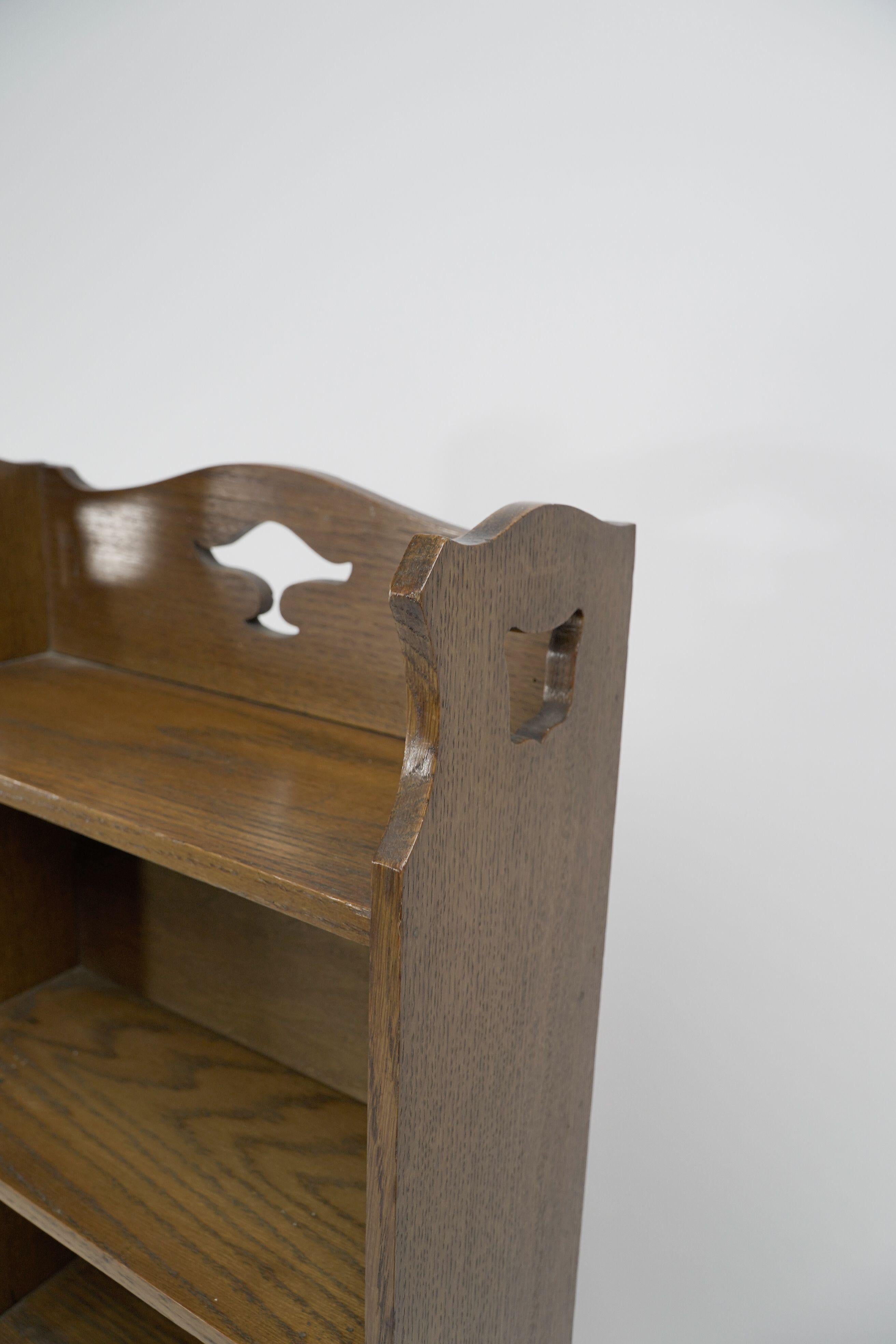 Liberty & Co. A slim Arts and Crafts oak bookcase with stylized floral cut-outs In Good Condition For Sale In London, GB