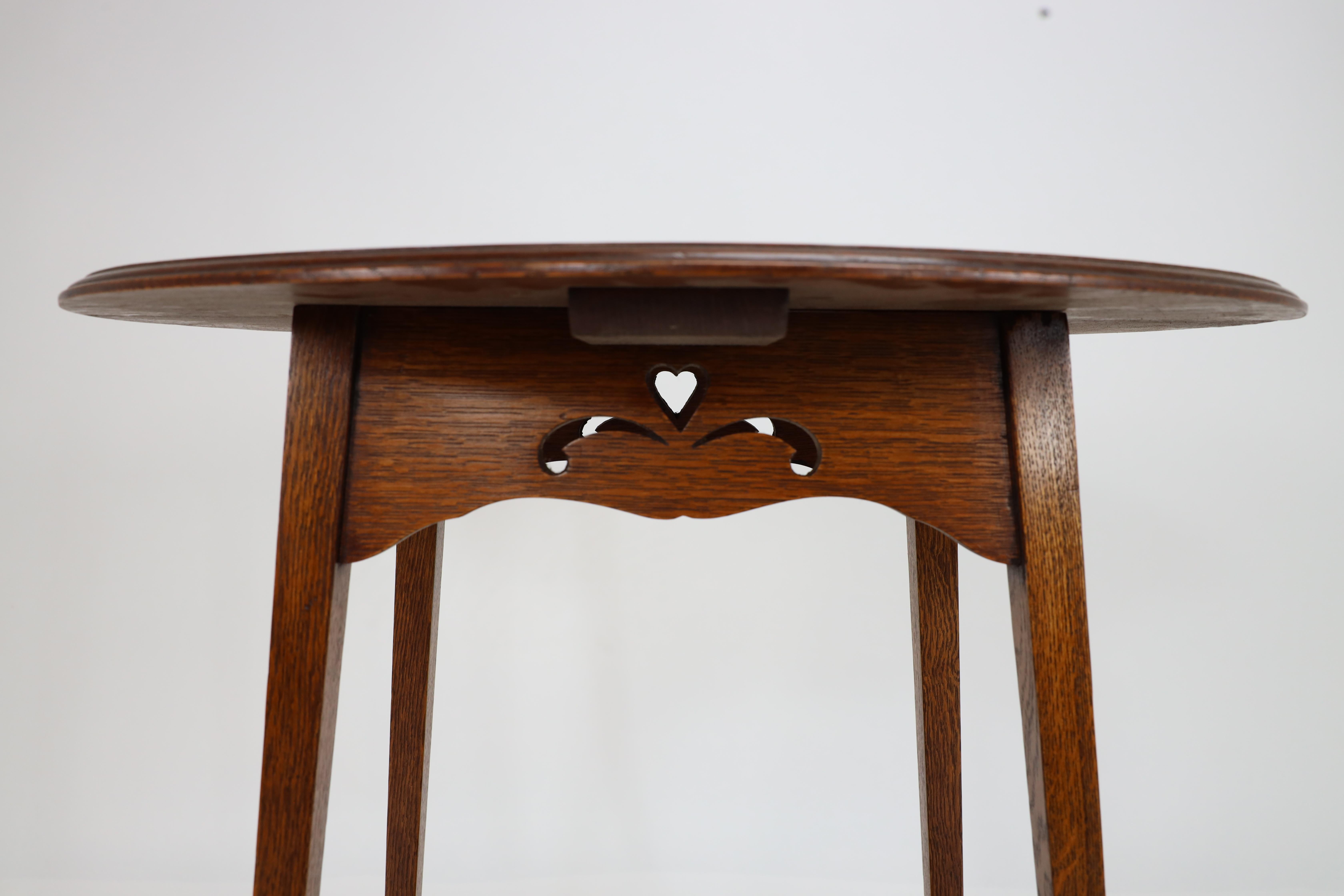 Liberty & Co. An Arts & Crafts oak oval top side table with heart cut-outs 9