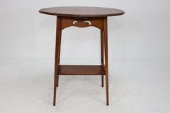 Liberty & Co. An Arts & Crafts oak oval top side table with heart cut-outs