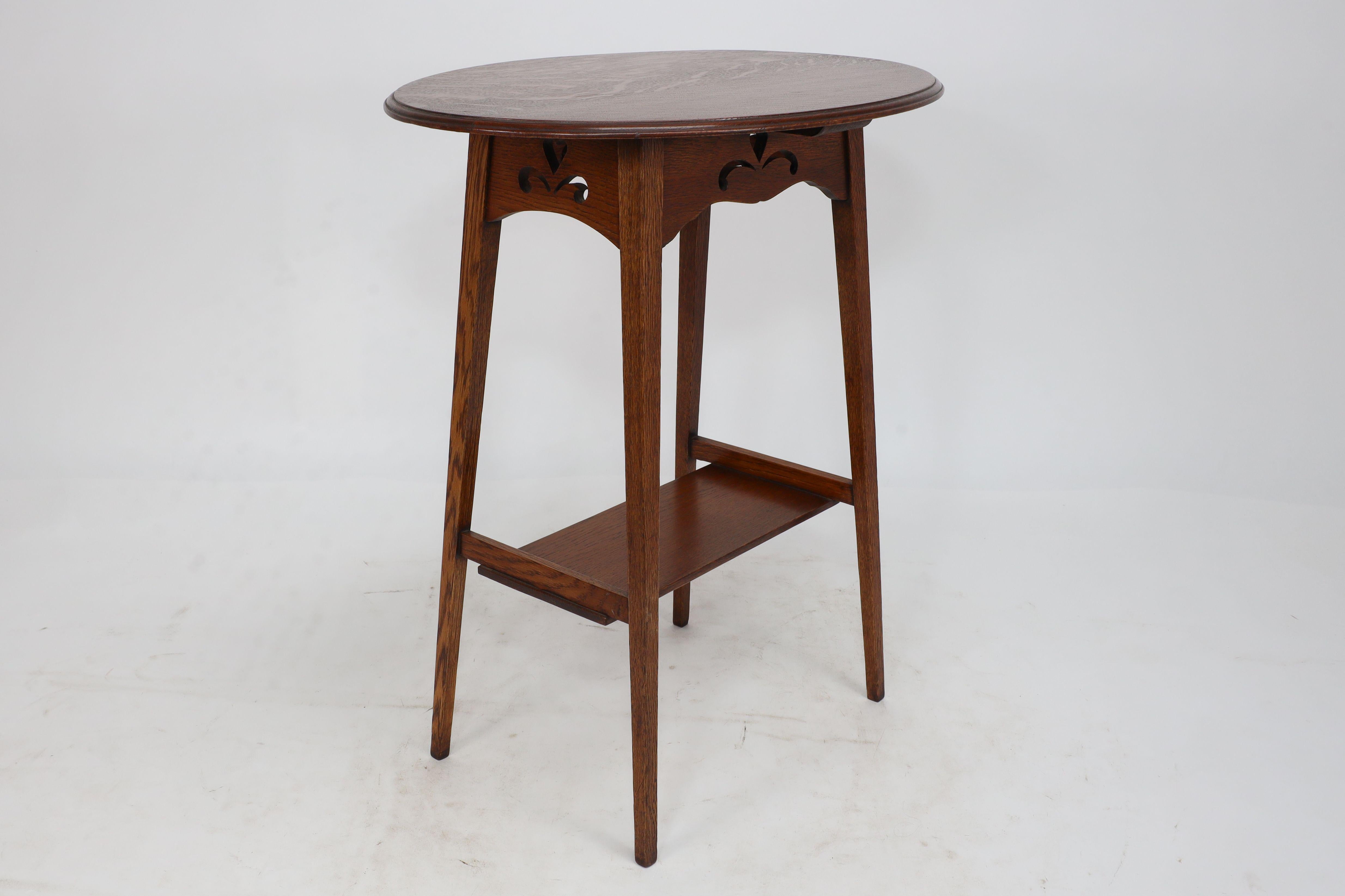 English Liberty & Co. An Arts & Crafts oak oval top side table with heart cut-outs