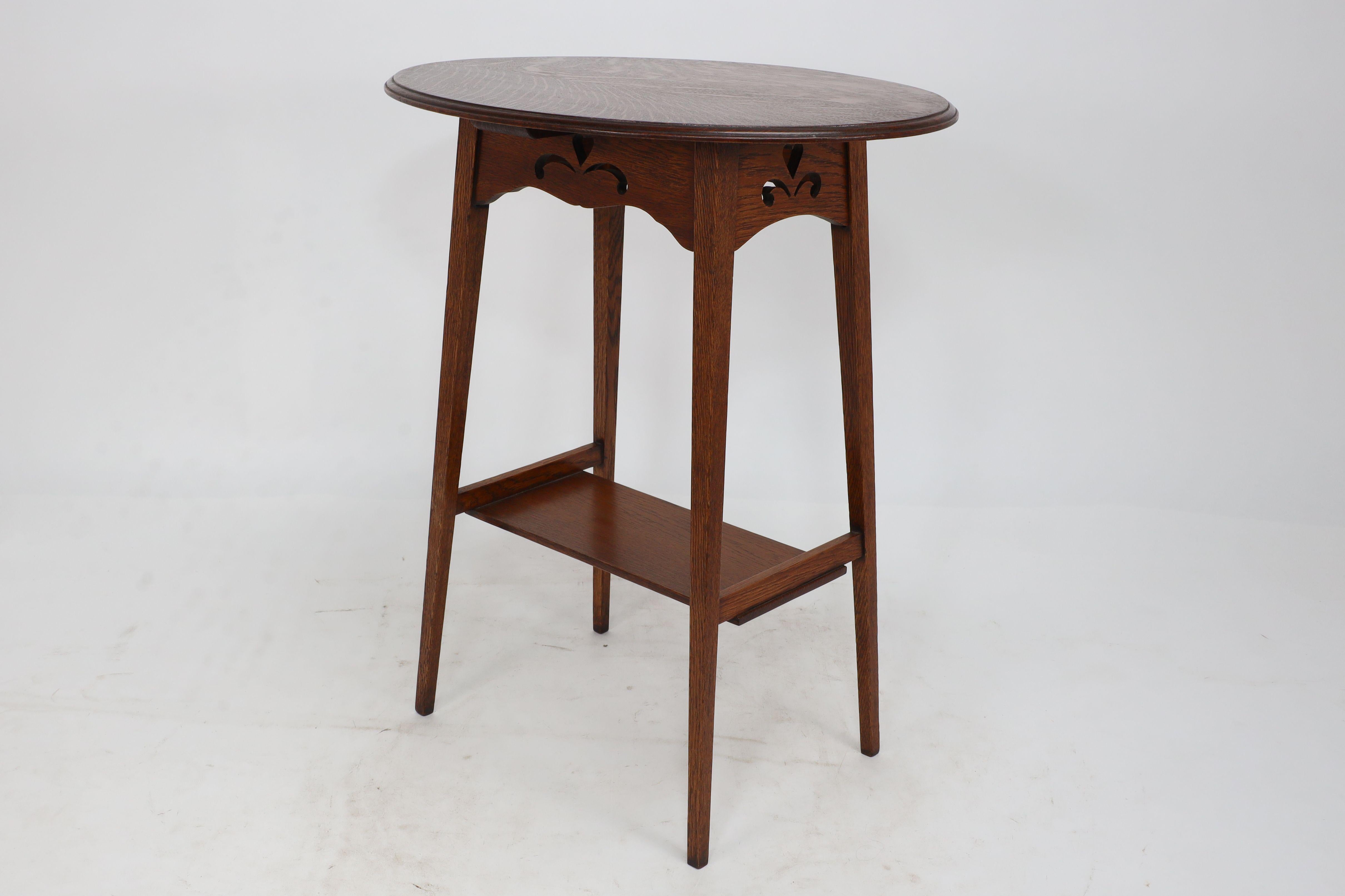 Early 20th Century Liberty & Co. An Arts & Crafts oak oval top side table with heart cut-outs