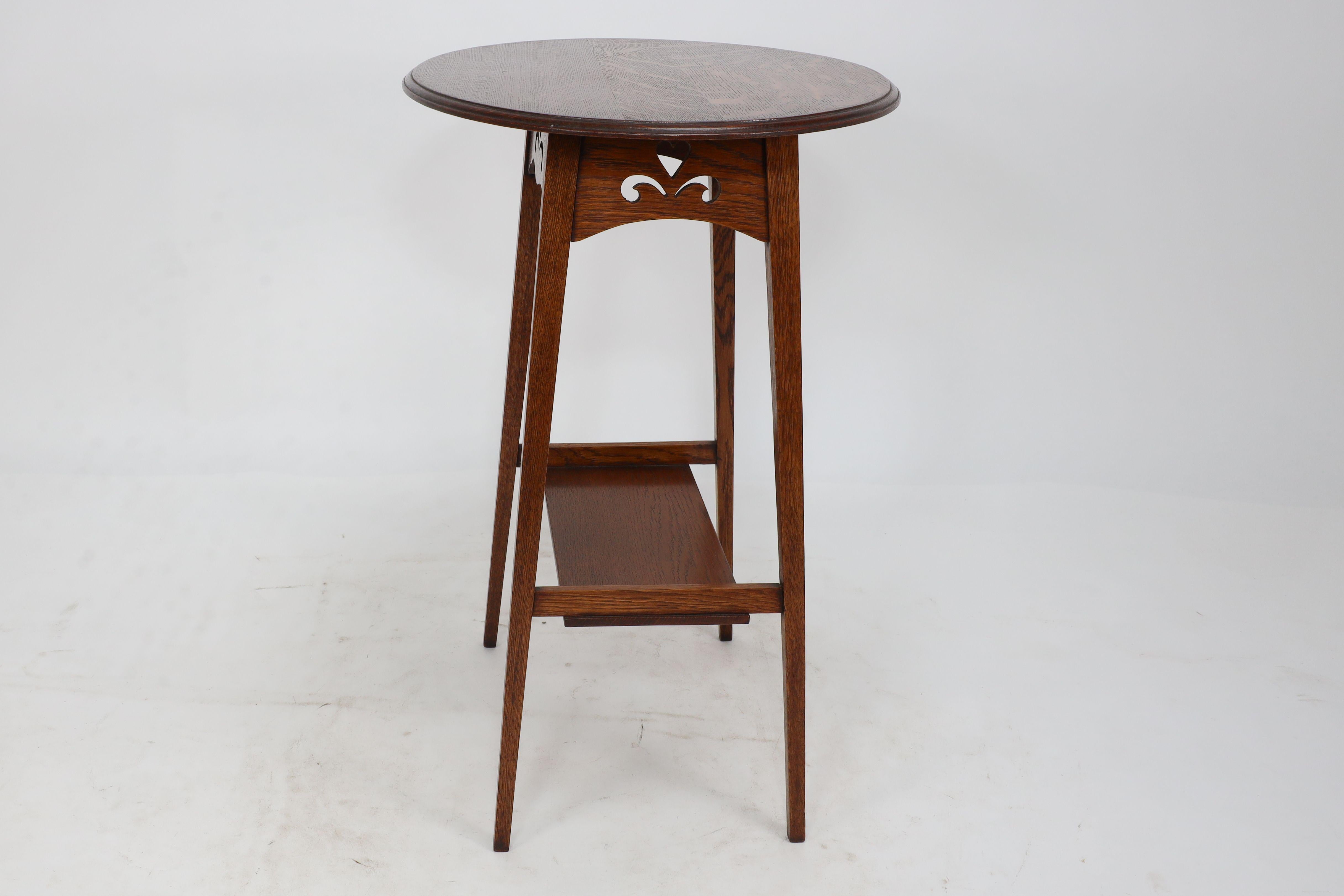 Oak Liberty & Co. An Arts & Crafts oak oval top side table with heart cut-outs