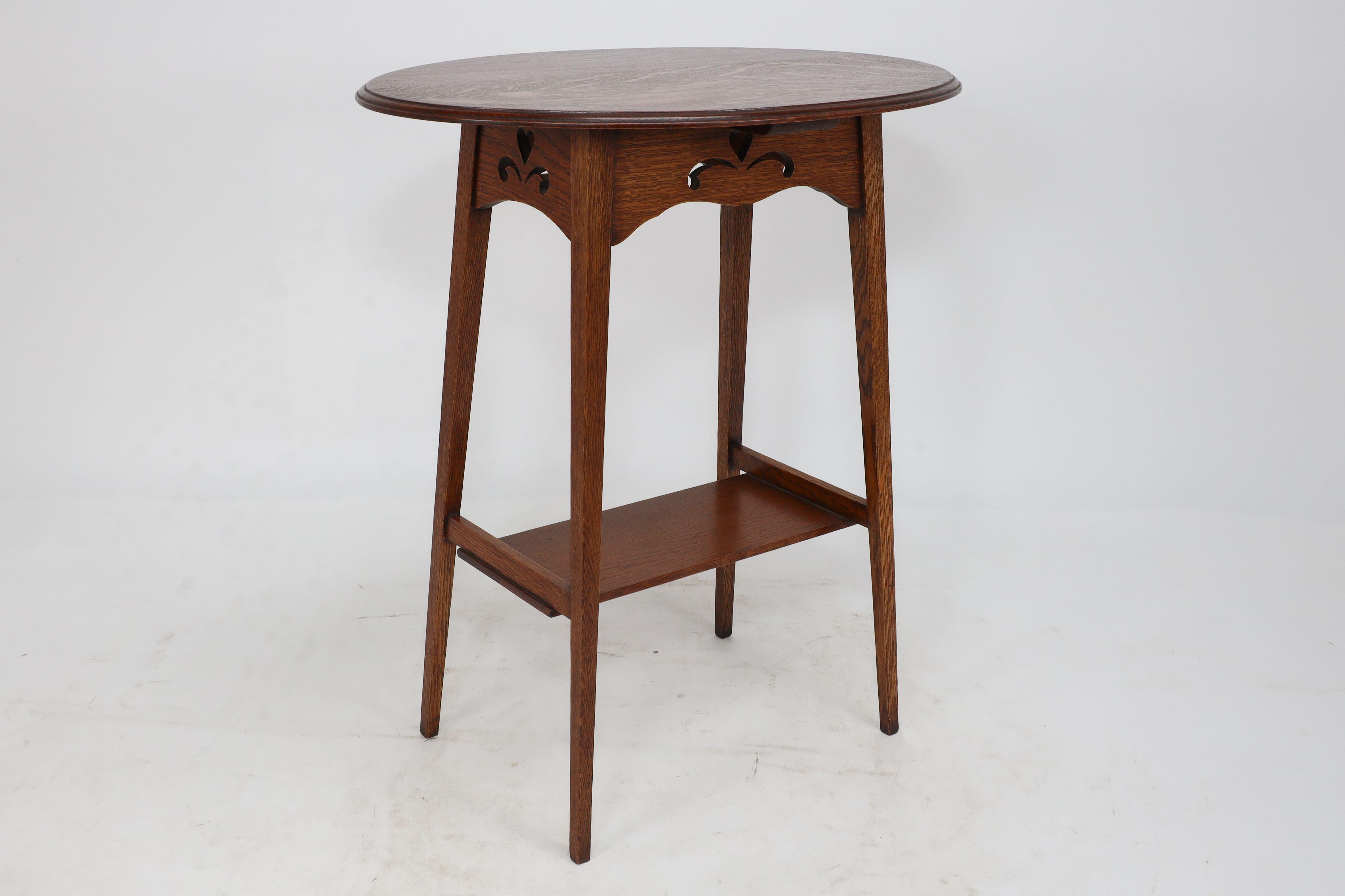 Liberty & Co. An Arts & Crafts oak oval top side table with heart cut-outs 1