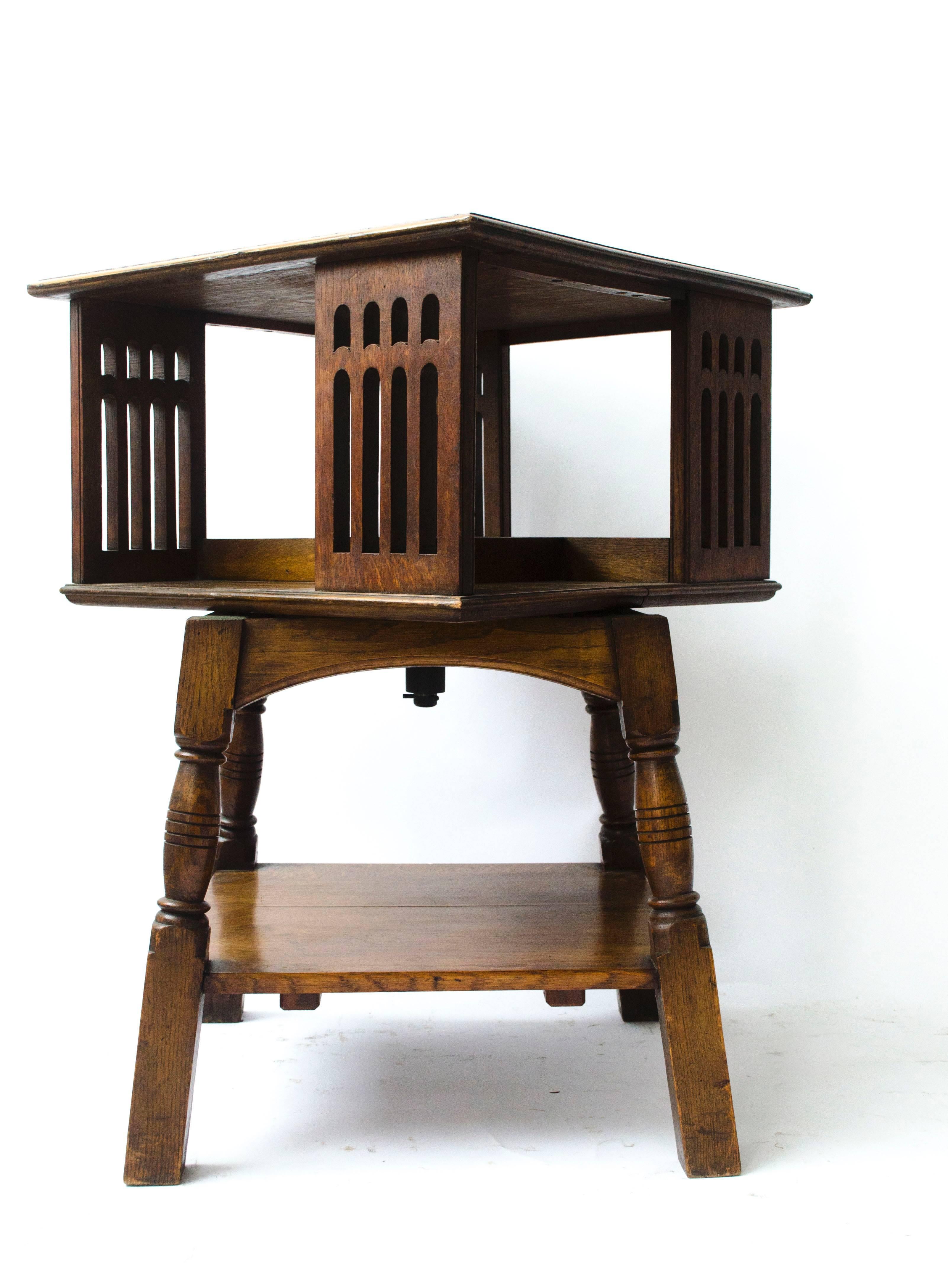 Liberty & Co. A rare Arts & Crafts oak revolving bookcase table on square and turned legs, united by a lower shelf.