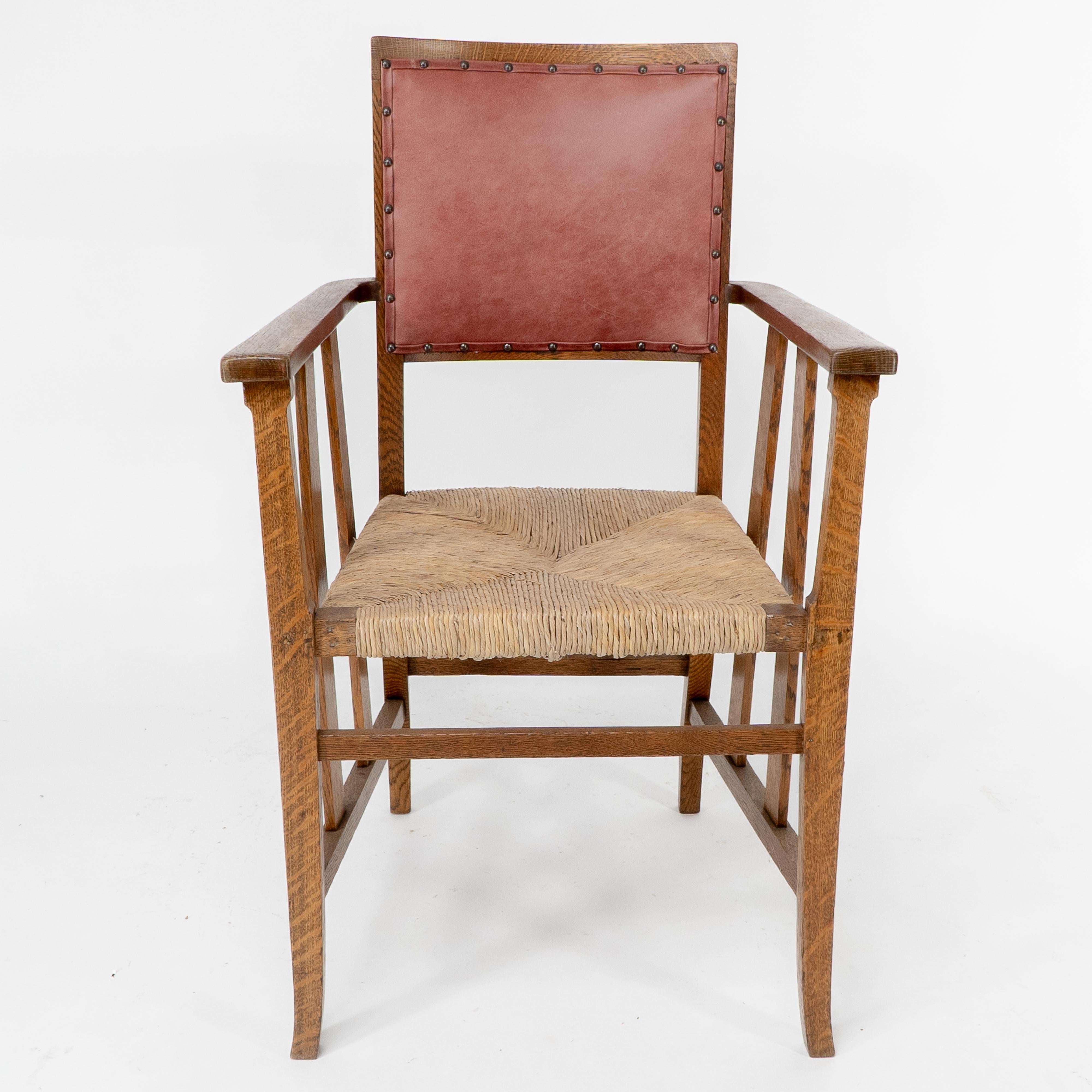 Liberty and Co. An Arts and Crafts rush seat armchair, with shaped back professionally reupholstered in a quality leather with slats running down from the arms past the seat to the side leg stretchers.