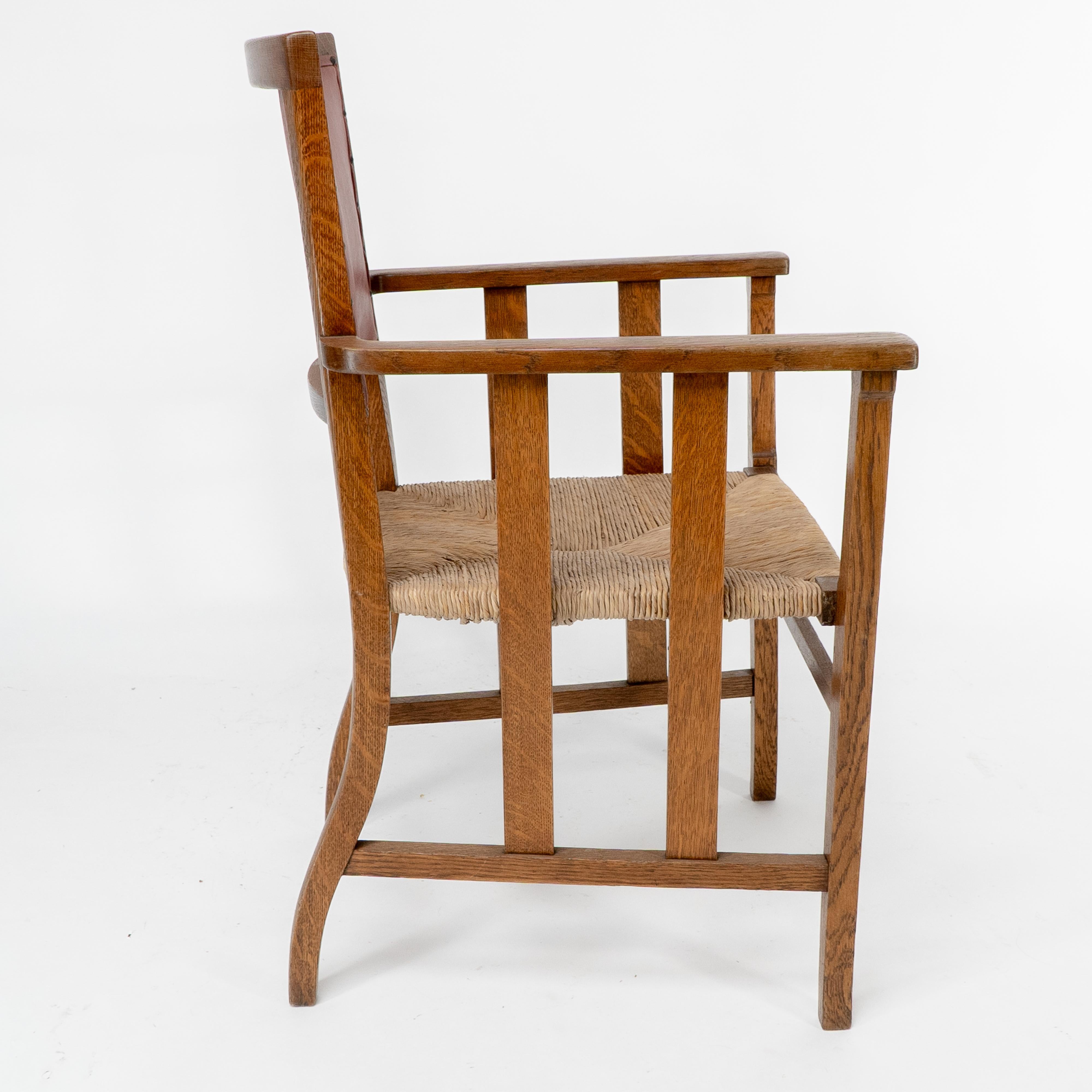 English Liberty & Co. An Arts & Crafts rush seat armchair with a shaped back For Sale