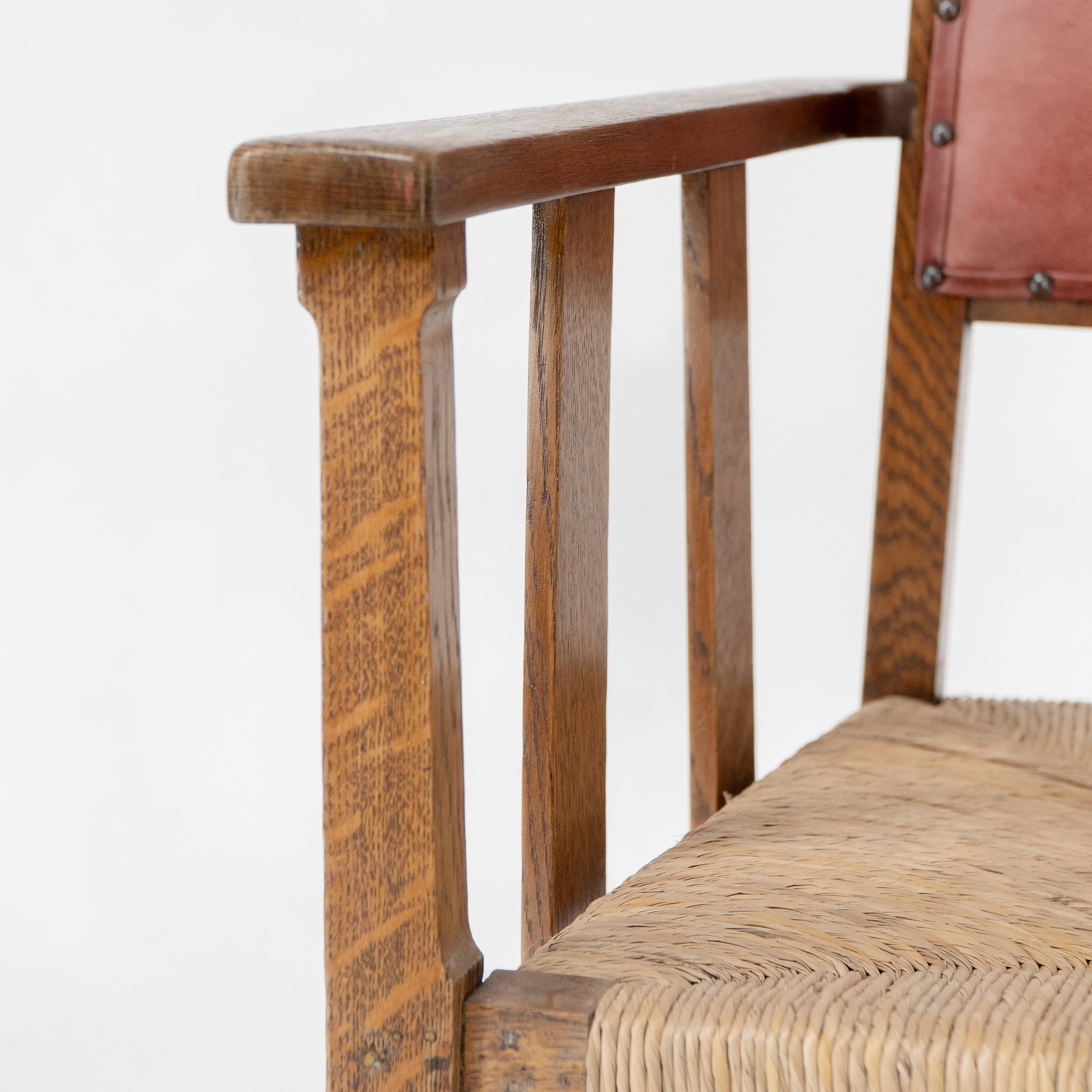 Rush Liberty & Co. An Arts & Crafts rush seat armchair with a shaped back For Sale