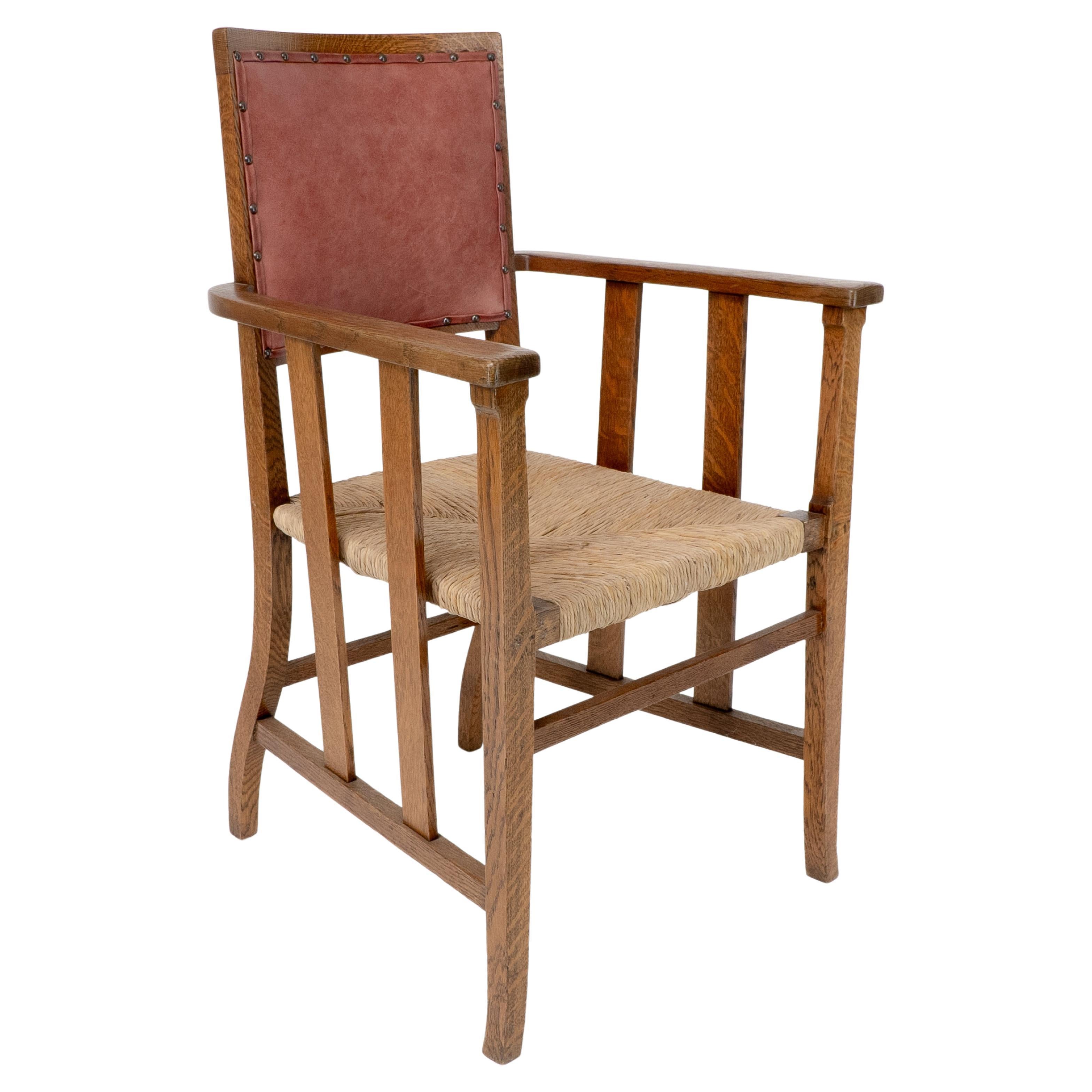 Liberty & Co. An Arts & Crafts rush seat armchair with a shaped back