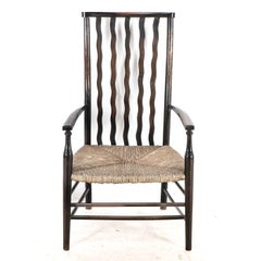 Liberty & Co. Una poltrona Arts & Crafts con seduta in giunco e schienale a doghe sagomate e ondulate