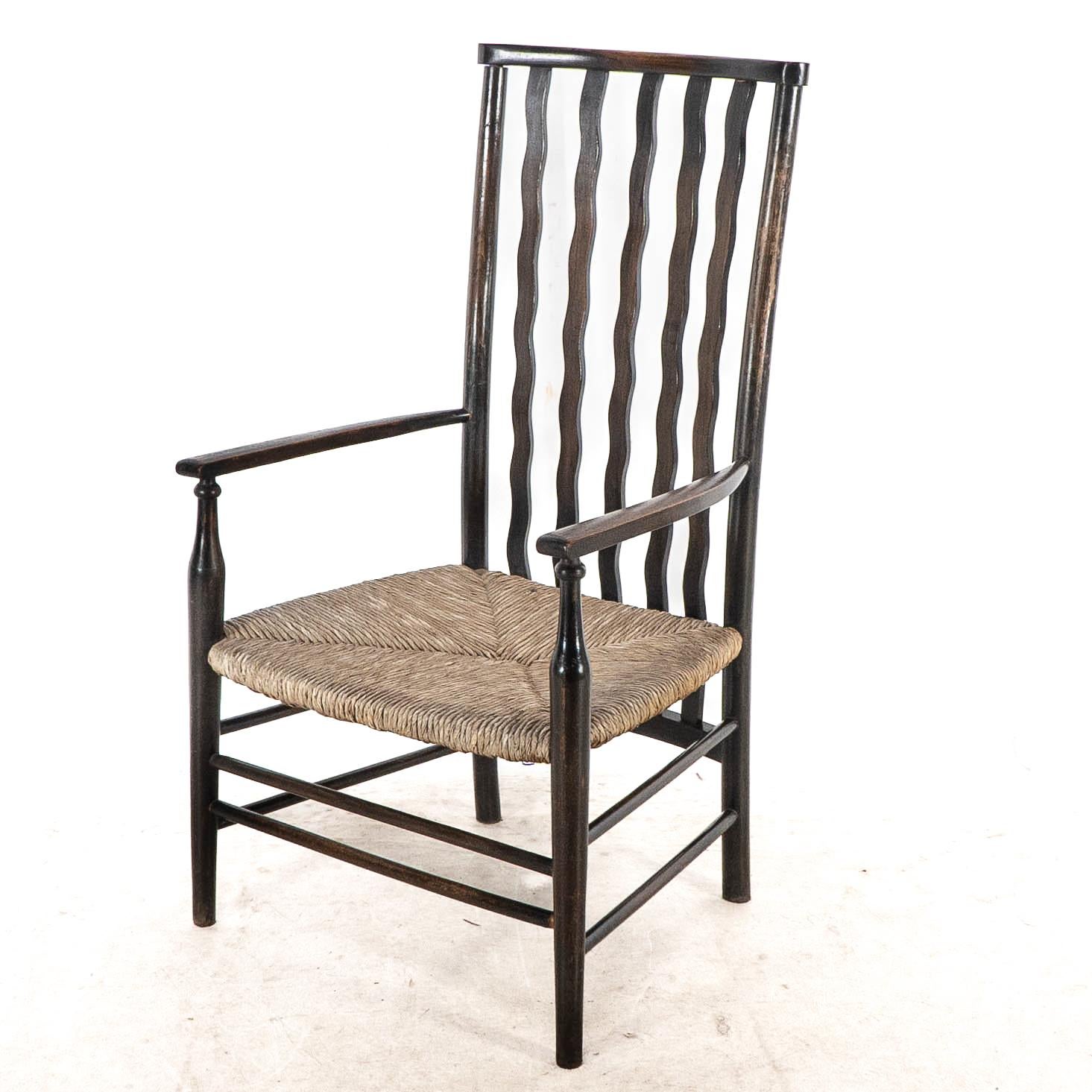 Arts and Crafts Liberty & Co. An Arts & Crafts rush seat armchair with wavy shaped back slats For Sale