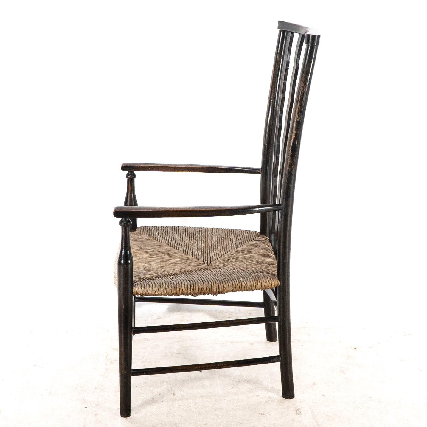 Liberty & Co. An Arts & Crafts rush seat armchair with wavy shaped back slats In Good Condition For Sale In London, GB
