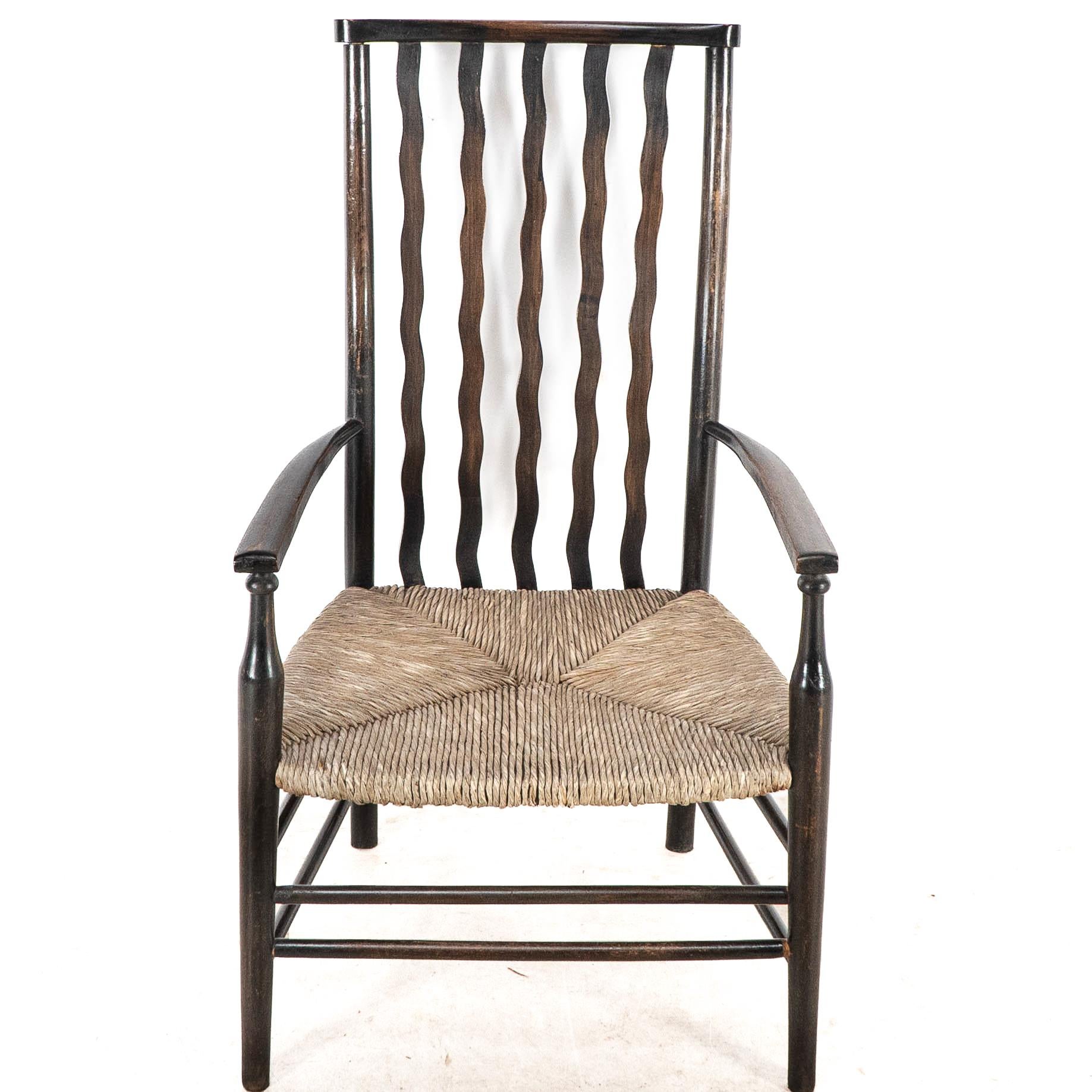Early 20th Century Liberty & Co. An Arts & Crafts rush seat armchair with wavy shaped back slats For Sale