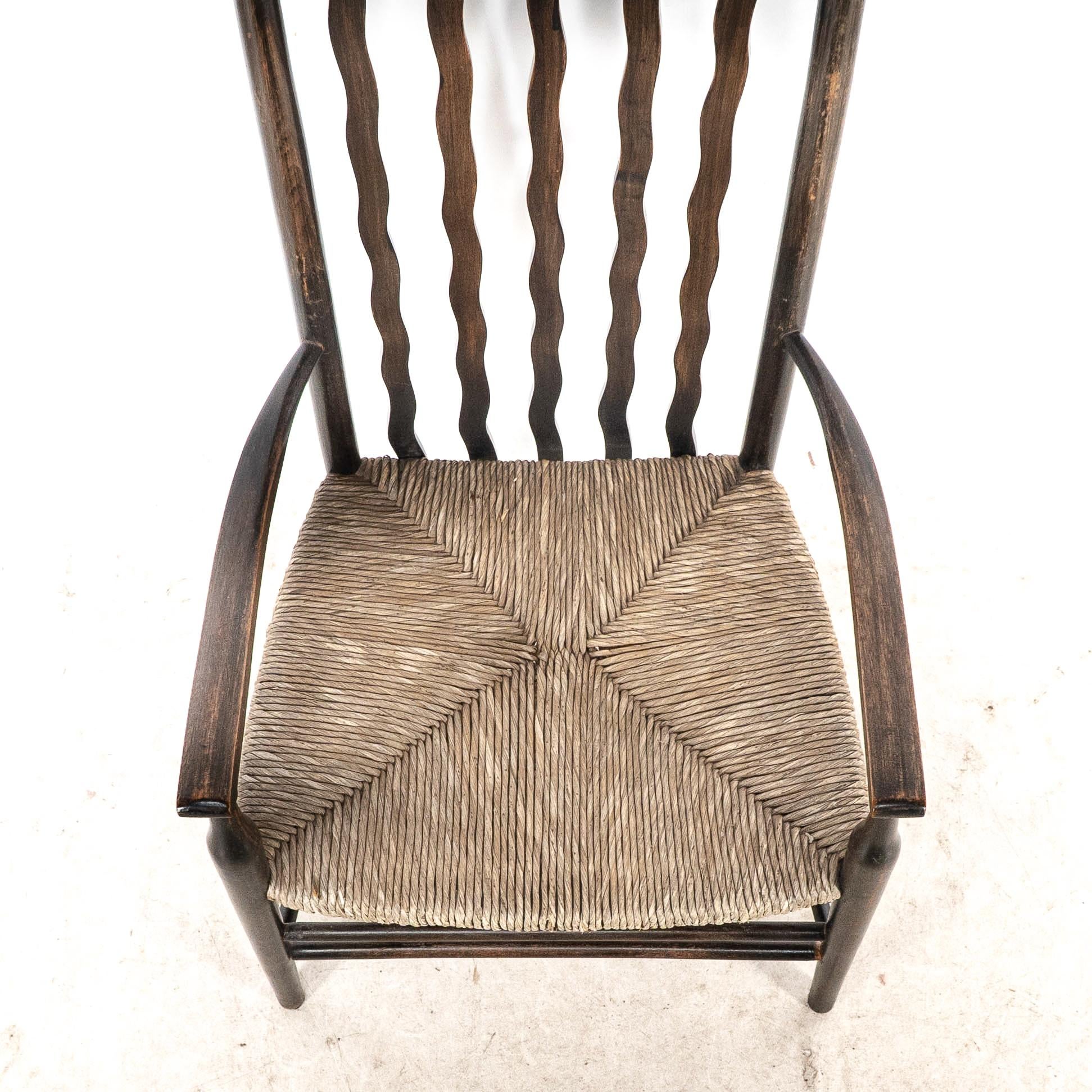 Liberty & Co. An Arts & Crafts rush seat armchair with wavy shaped back slats For Sale 2