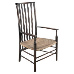 Liberty & Co. An Arts & Crafts rush seat armchair with wavy shaped back slats