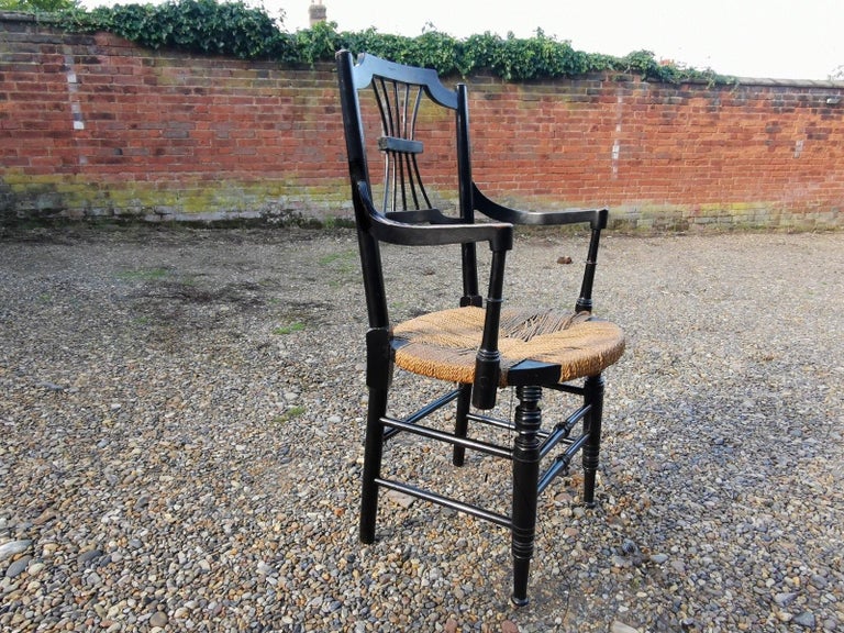 Liberty & Co. In the style of Morris and Co's Sussex range.
An English Aesthetic Movement ebonized rush-seat Sussex style armchair after a design by Daniel Gabriel Rossetti in original condition with original seagrass seat with brass buttons