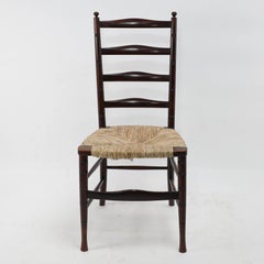 Liberty & Co. An English Aesthetic Movement walnut ladder back rush seat chair