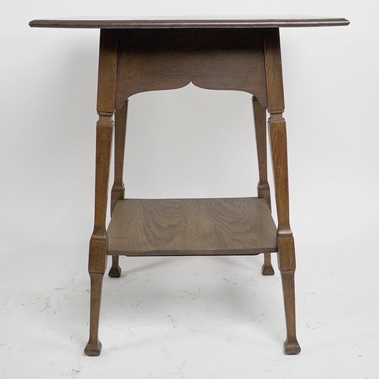 Liberty and Co (attributed). An Arts and Crafts oak two tier side table with Moorish aprons underneath the top.
