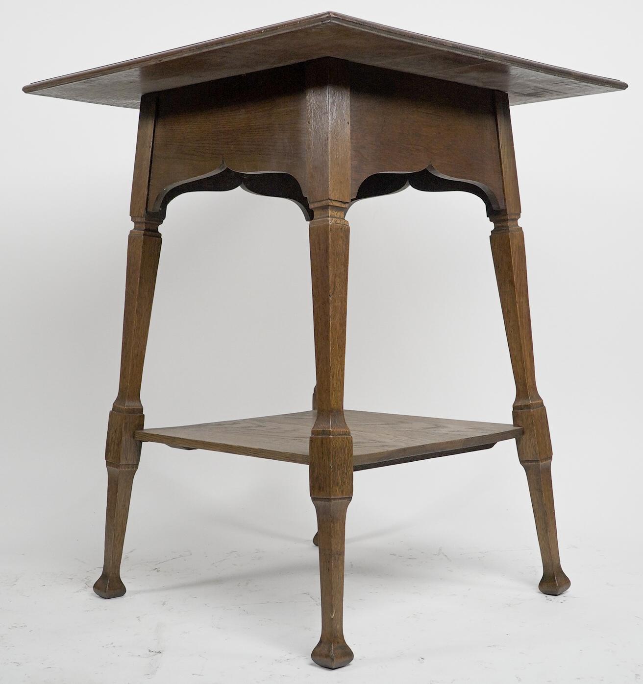 English Liberty & Co. An Arts & Crafts oak two tier side table with Moorish aprons. For Sale