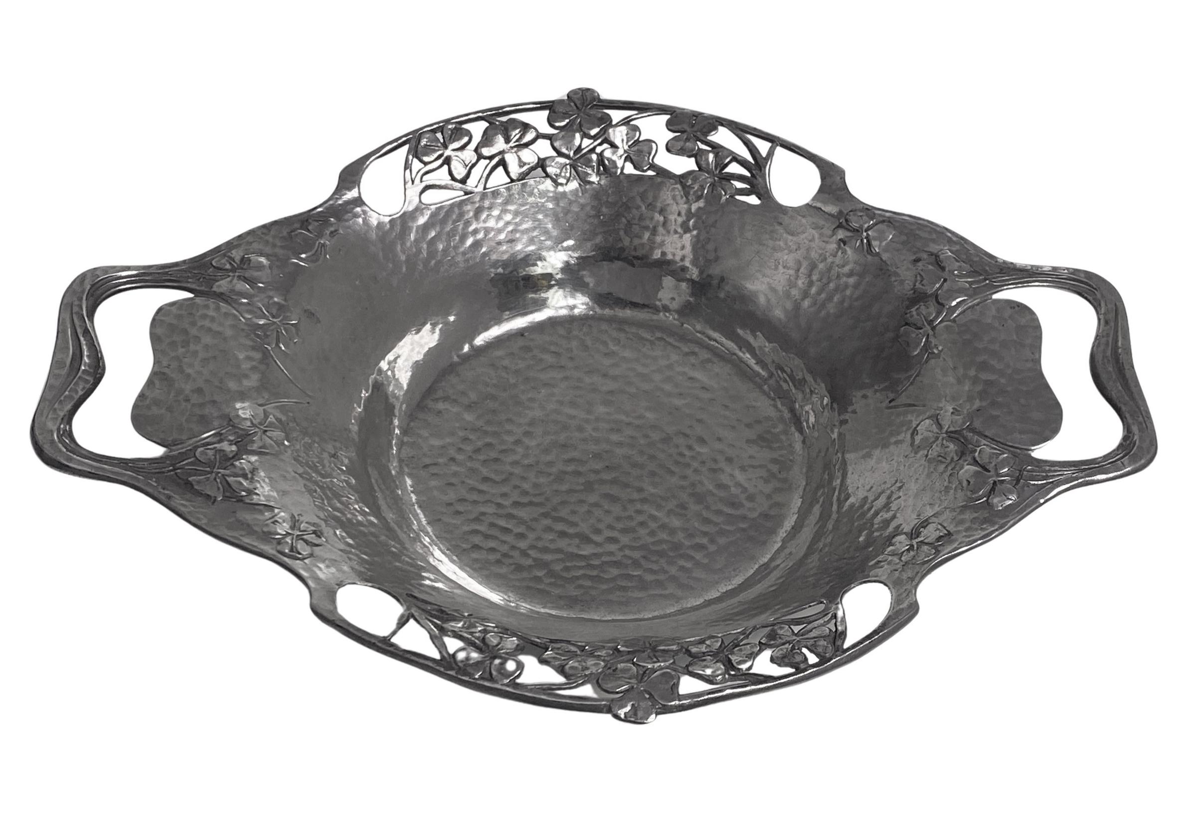 Liberty Arts and Crafts Tudric Pewter Dish, Liberty & Co, English, circa 1903. The two handled hammered dish with stylized cut out handles in a heart shape with a pierced surround of shamrocks, welled interior. Stamped Made in England 0287