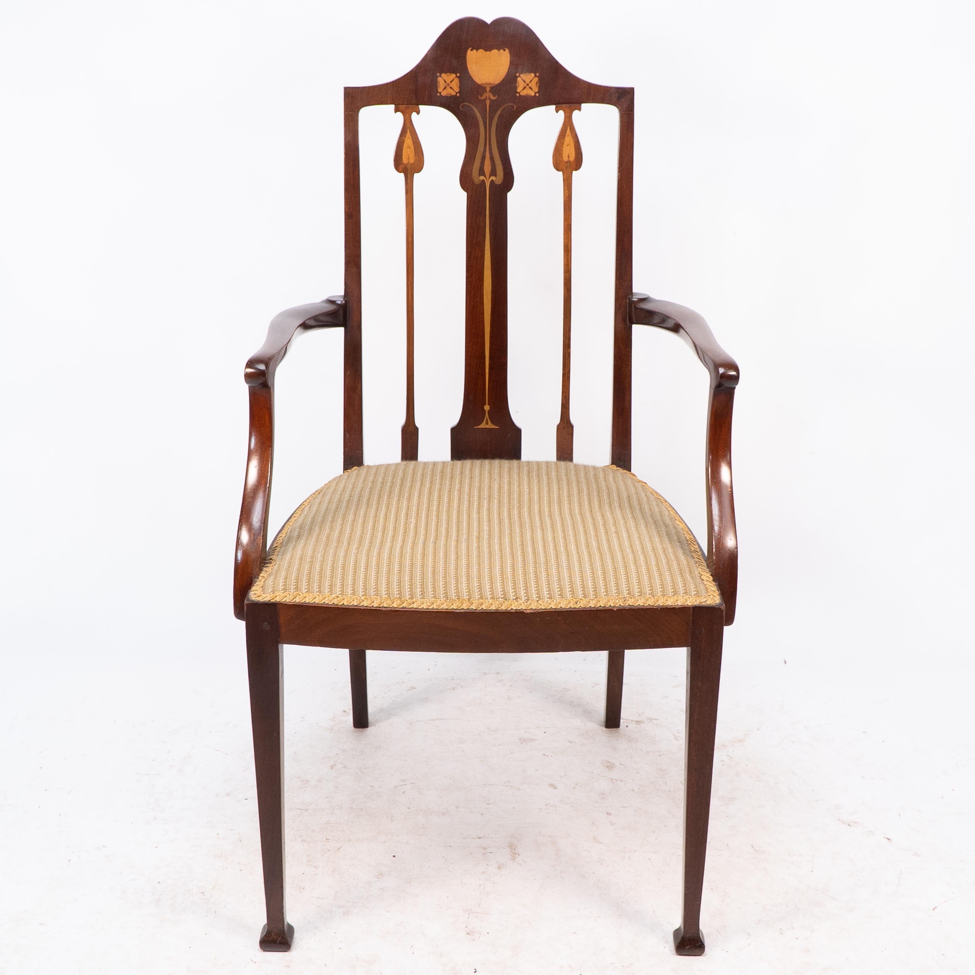 Liberty and Co. An Arts and Crafts mahogany armchair with stylized fruitwood floral inlaid decoration to the backrest and sculpted arms. Seat Height: 45 cm Arm Height: 66 cm