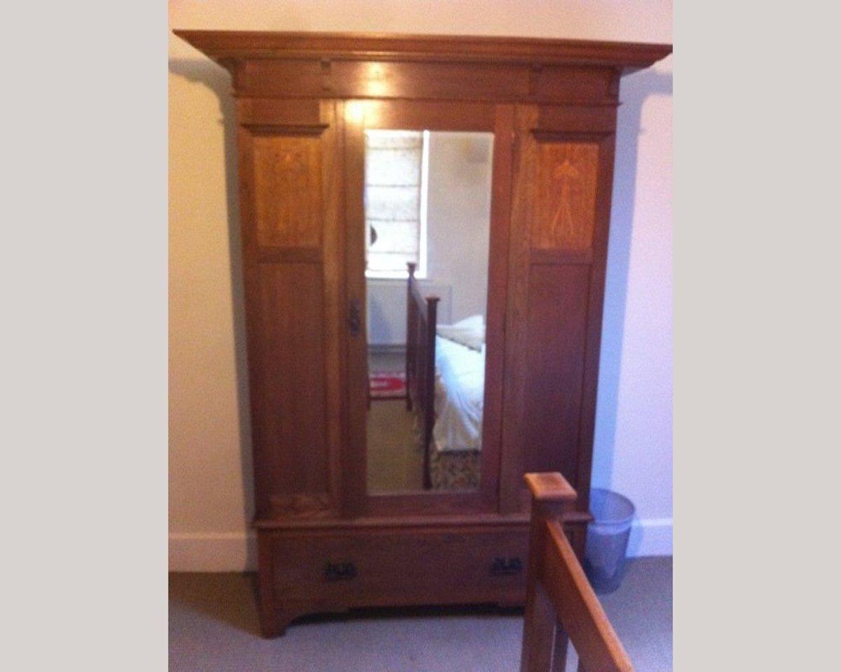Liberty & Co, attributed.
A Glasgow style Arts & Crafts oak bedroom pair consisting of a wardrobe and a 57 inch wide double bed.
The wardrobe with a flaring cornice, a full length original bevelled mirror to the door, flanked by upper stylized
