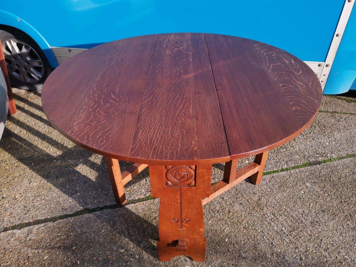 Liberty & Co.,
An Arts & Crafts, drop leaf oak dining table with carved rose head floral decoration to each end united at the base with through pegged tennon construction and made from quarter sawn oak, giving a wonderful figuring to the grain. I