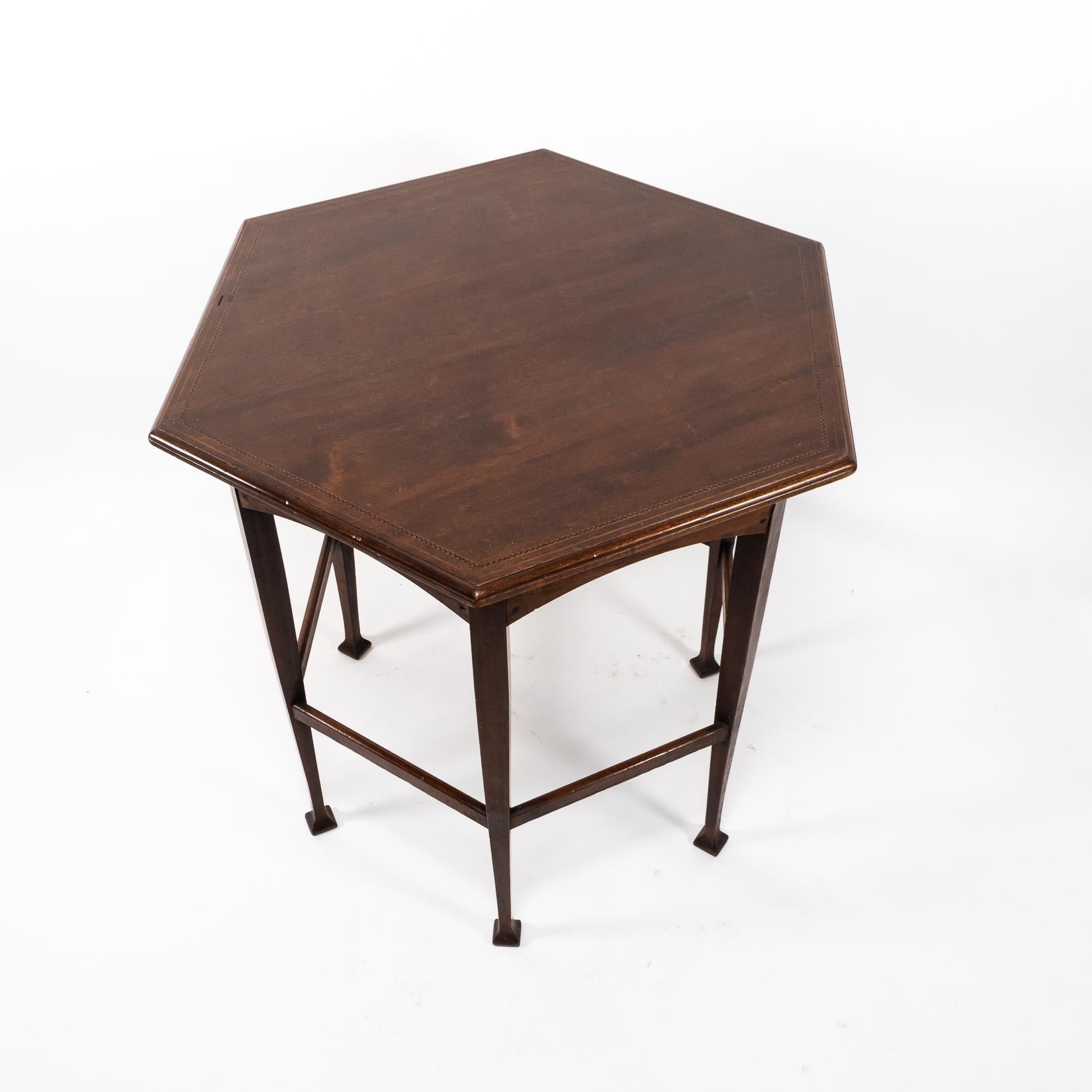 Liberty & Co. zugeschrieben
Ein sechseckiger Beistelltisch der Ästhetischen Bewegung mit Fischgräteneinlage am Rand der Platte und einer geformten Kante mit geformten Schürzen darunter. Er steht auf sechs Beinen, die durch Bänder mit quadratischen