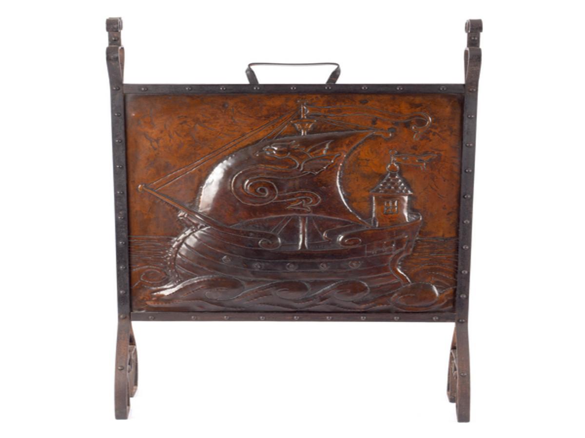 Liberty & Co., attributed to John Pearson or John Williams.
An Arts & Crafts copper and wrought iron fire-screen, with cold rivetted construction to the edges and a hand-hammered galleon decorated with a dragon to the sail. The feet with stylized