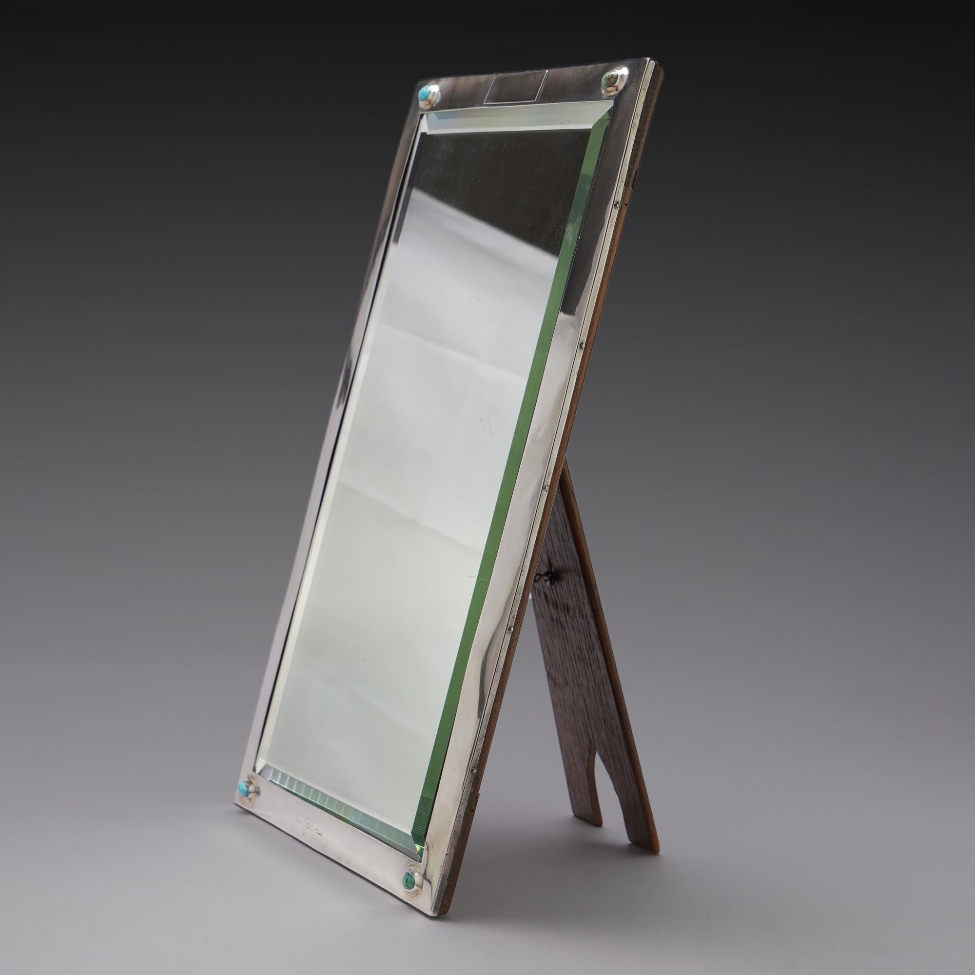 Liberty & Co. silver and turquoise table mirror with wooden back.
Made in England, London, 1900
Maker: Liberty & Co.
Fully hallmarked.

Dimensions:
Size 33.8 x 21.5 x 16.5 cm
Weight 1230 grams

Condition: Mirror has some general wear and