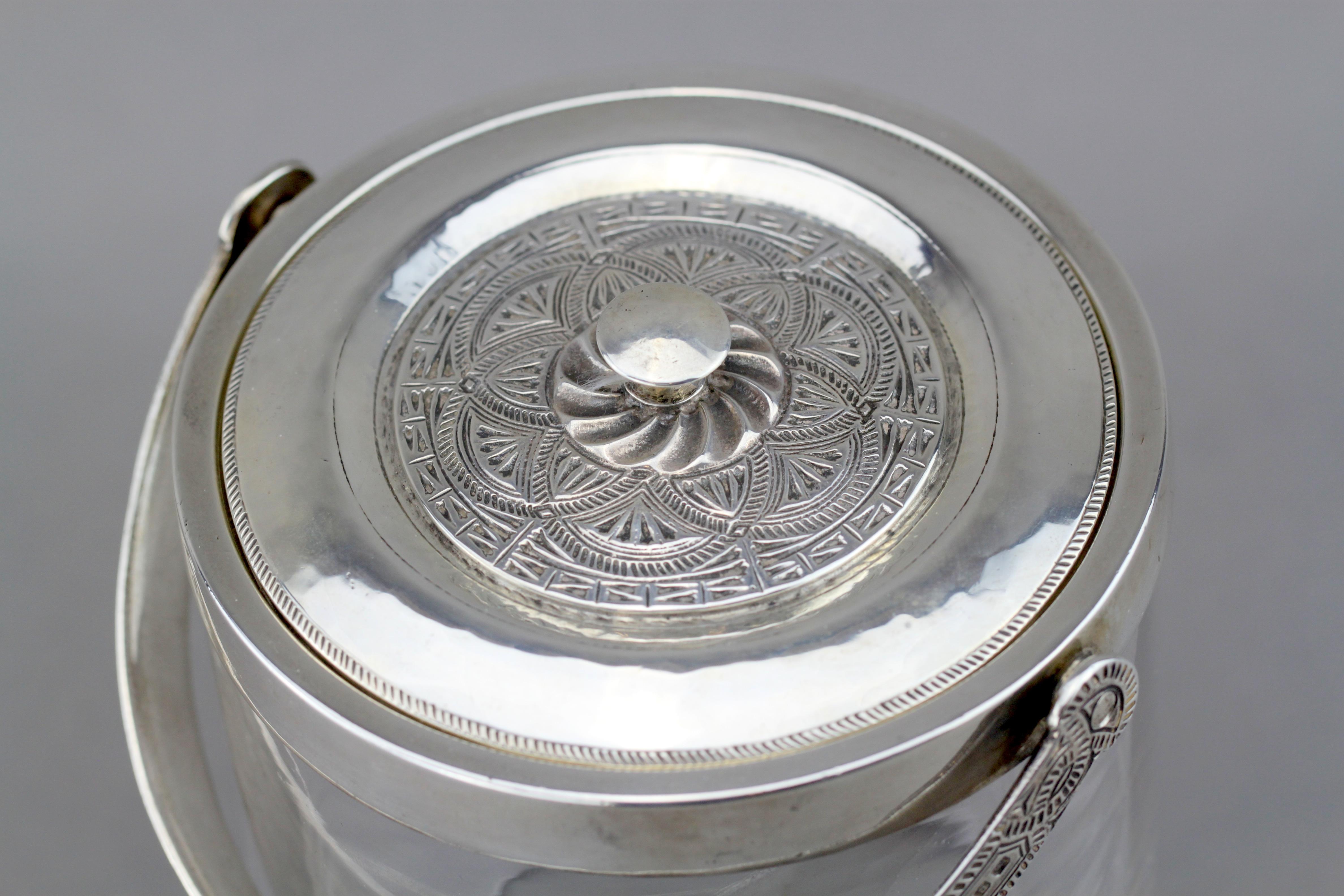 A sterling silver and glass ice bucket
Maker: Liberty & Co
Made in Birmingham 1917
Fully hallmarked.

Dimensions:
Diameter x height 12.8 x 14.5 cm
Weight: 1006 grams.

Condition: Surface wear and tear from general usage, has some subtle age