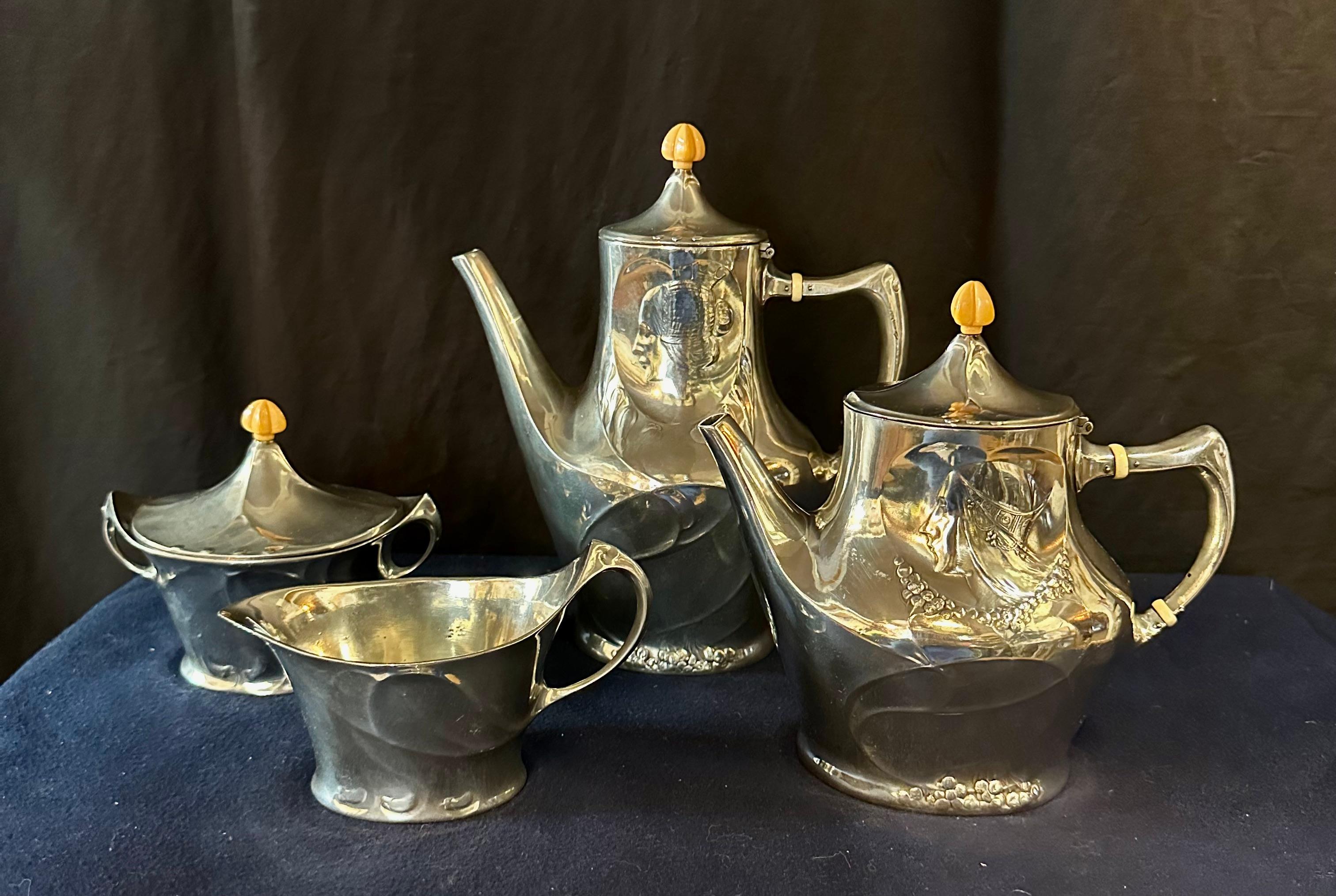 This vintage early 20th century tea service with serving tray is designed & produced by “Liberty & Co.”. The high polished pewter pieces are decorated with stylish, but distinctive Art Nouveau period motifs over its surfaces. On the tray, one finds