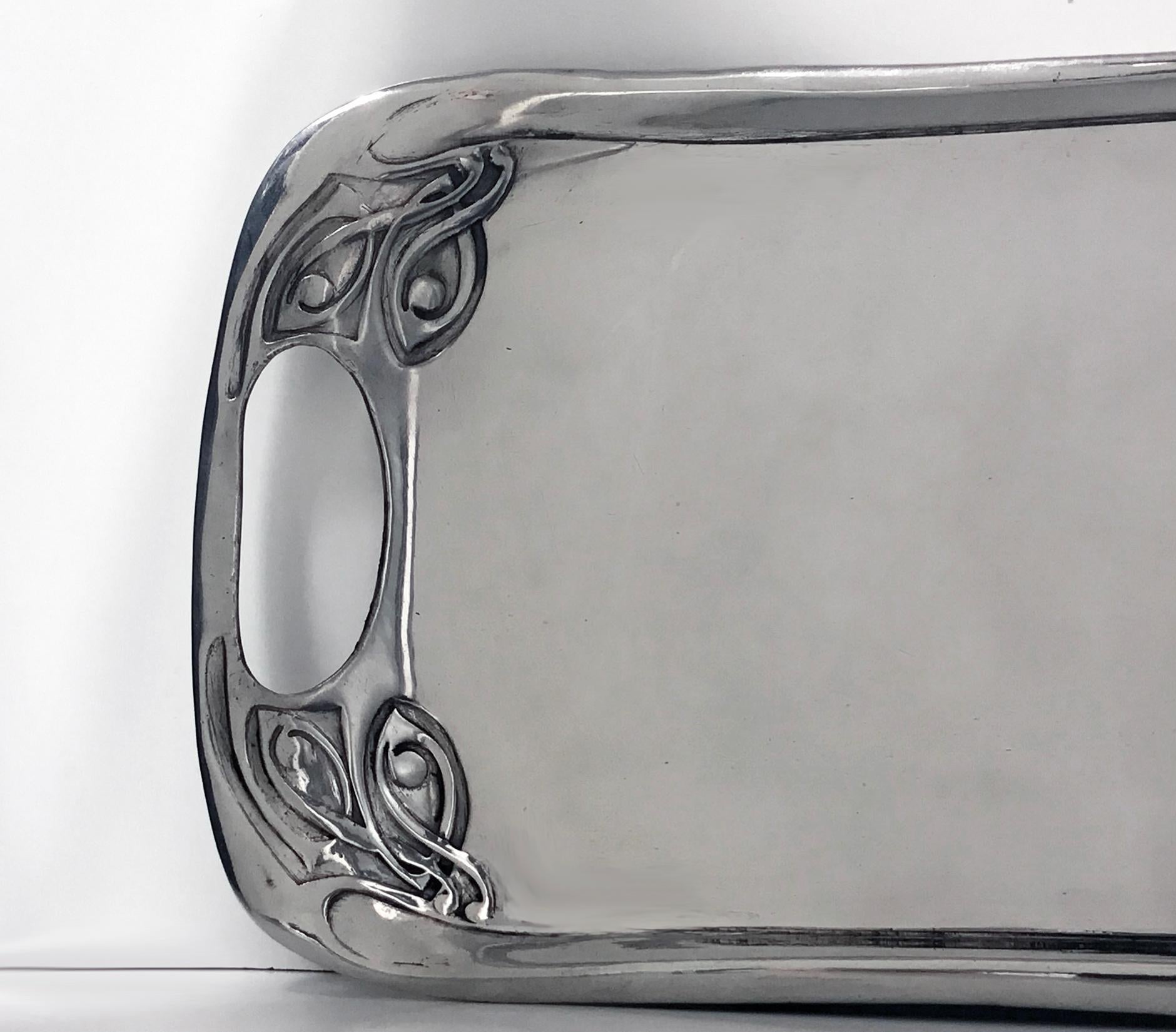 Liberty & Co polished pewter tray, designed by Archibald Knox, 1902-1905 design number 0309. Measures: 12.25 x 6.25 inches. The tray centre plain with open kidney handles and cornices of intertwining Celtic knot decoration. Liberty Trudric marks