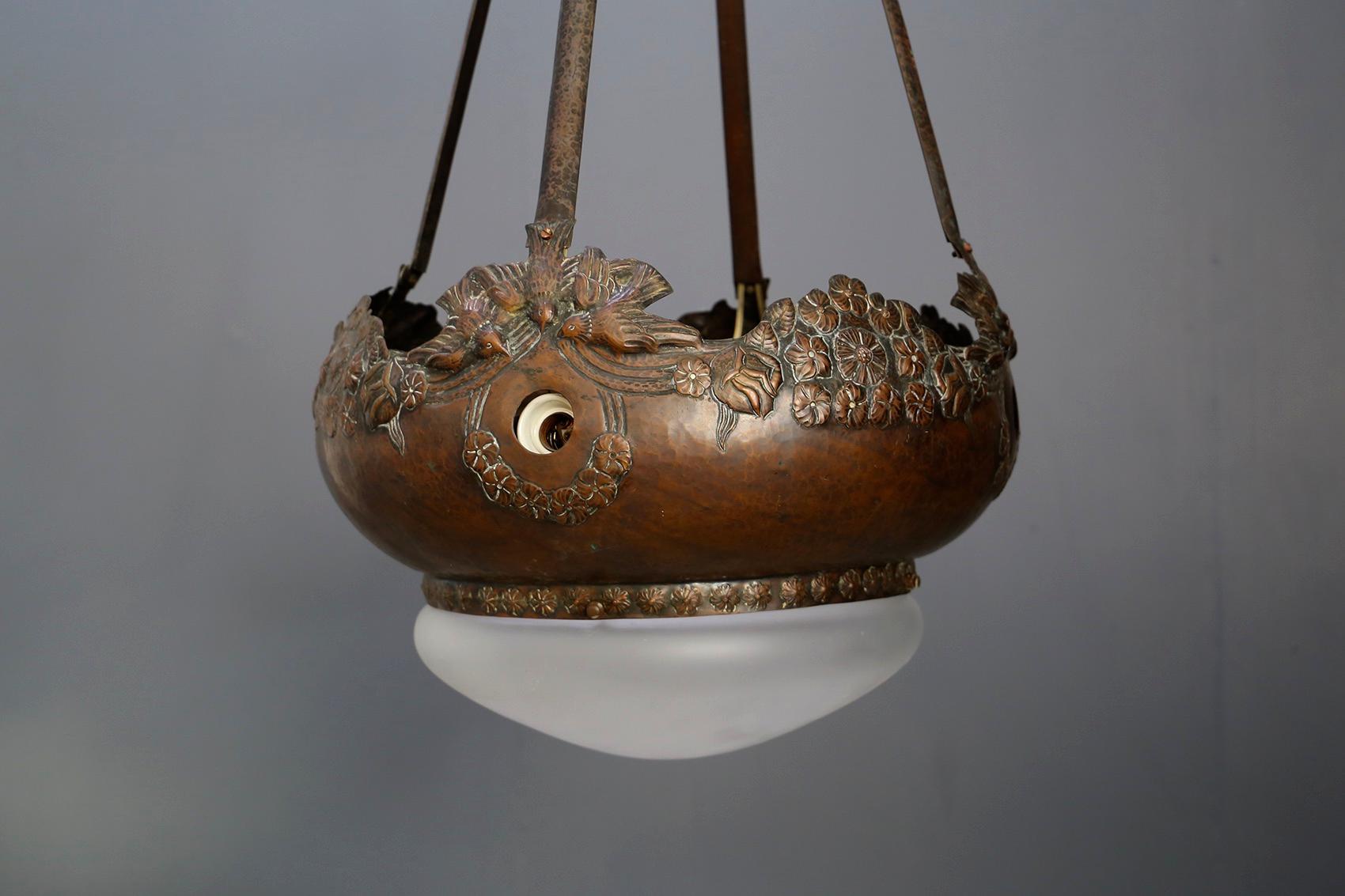 Large French Liberty style pendant chandelier. The chandelier is made of finely sculpted copper. As the Art Nouveau style wants we find floral elements well sculpted in copper to finish as an ornament. As lampshade to its lighting we find a semi