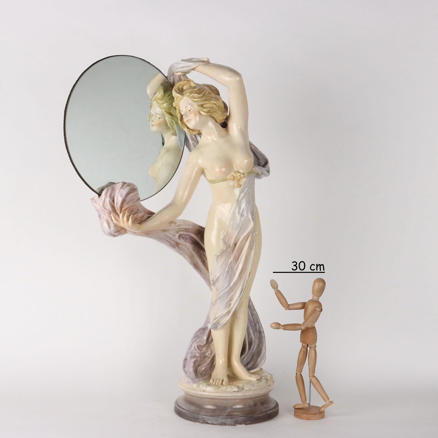 Glazed ceramic sculpture in soft colors depicting Venus. The statue holds a circular mirror and has a hardly legible manufacturing mark under the base.