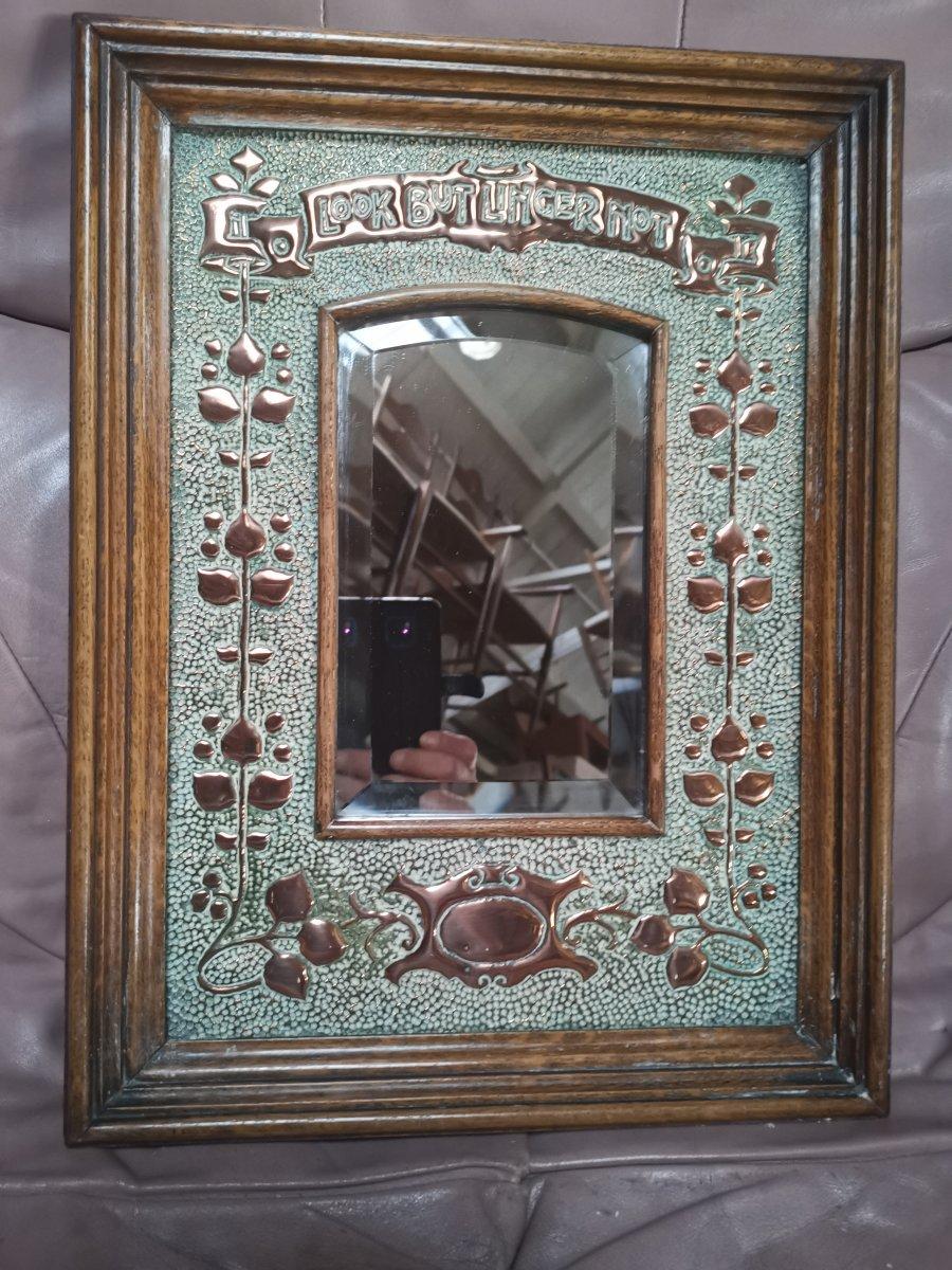 Liberty style, Art & Crafts copper mirror with stylized floral hand-hammered details flourishing the sides and a motto to the top that reads:- 'Look But Linger Not'.
In wonderful original condition retaining the original beveled mirror.