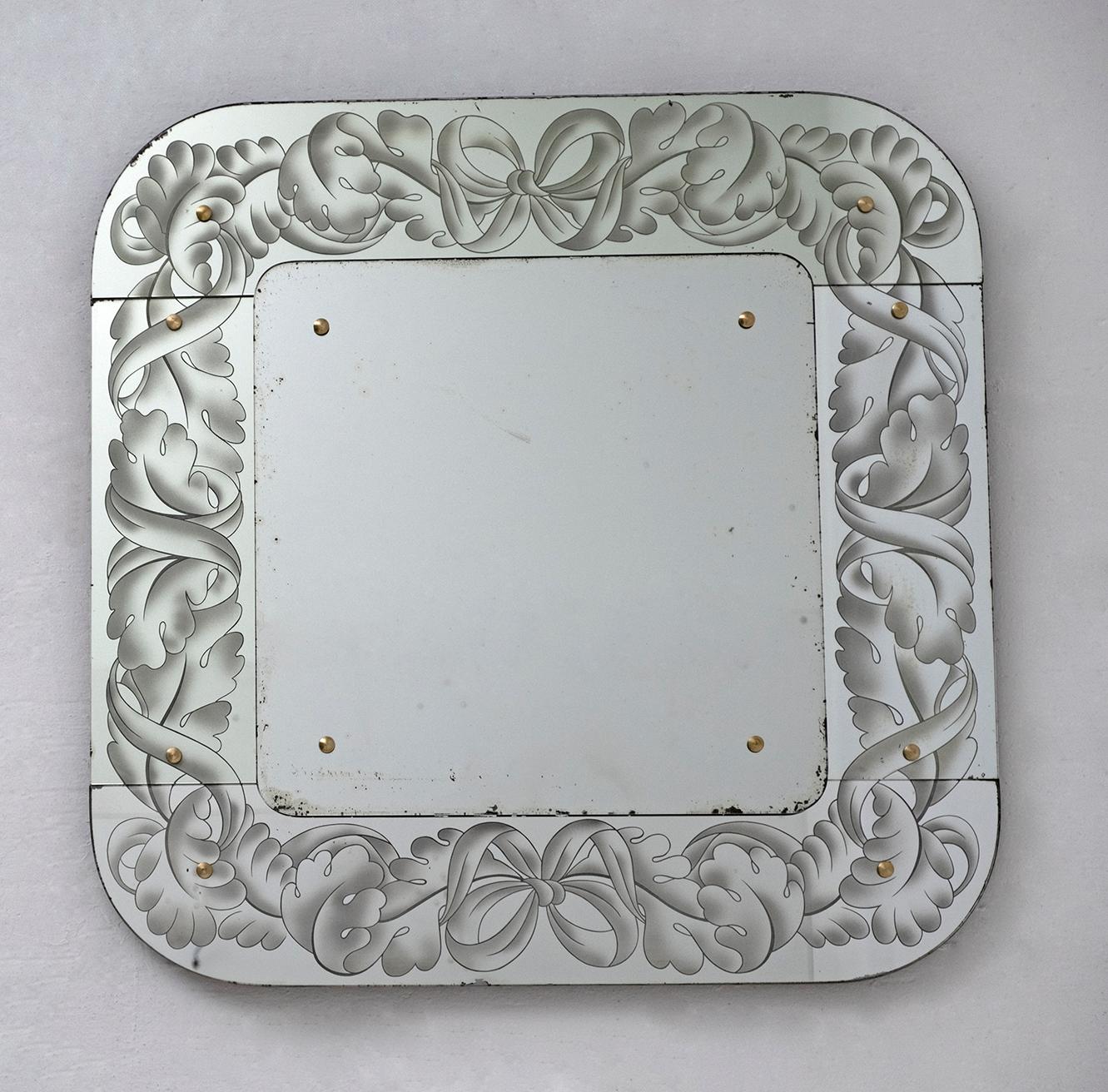 This elegant Venetian Art Nouveau mirror was made in Italy, in the 1950s. It has a square shape with rounded corners, mirrors engraved around it with Art Nouveau decorations and a mirror in the center. With its charming yet refined aesthetic, this