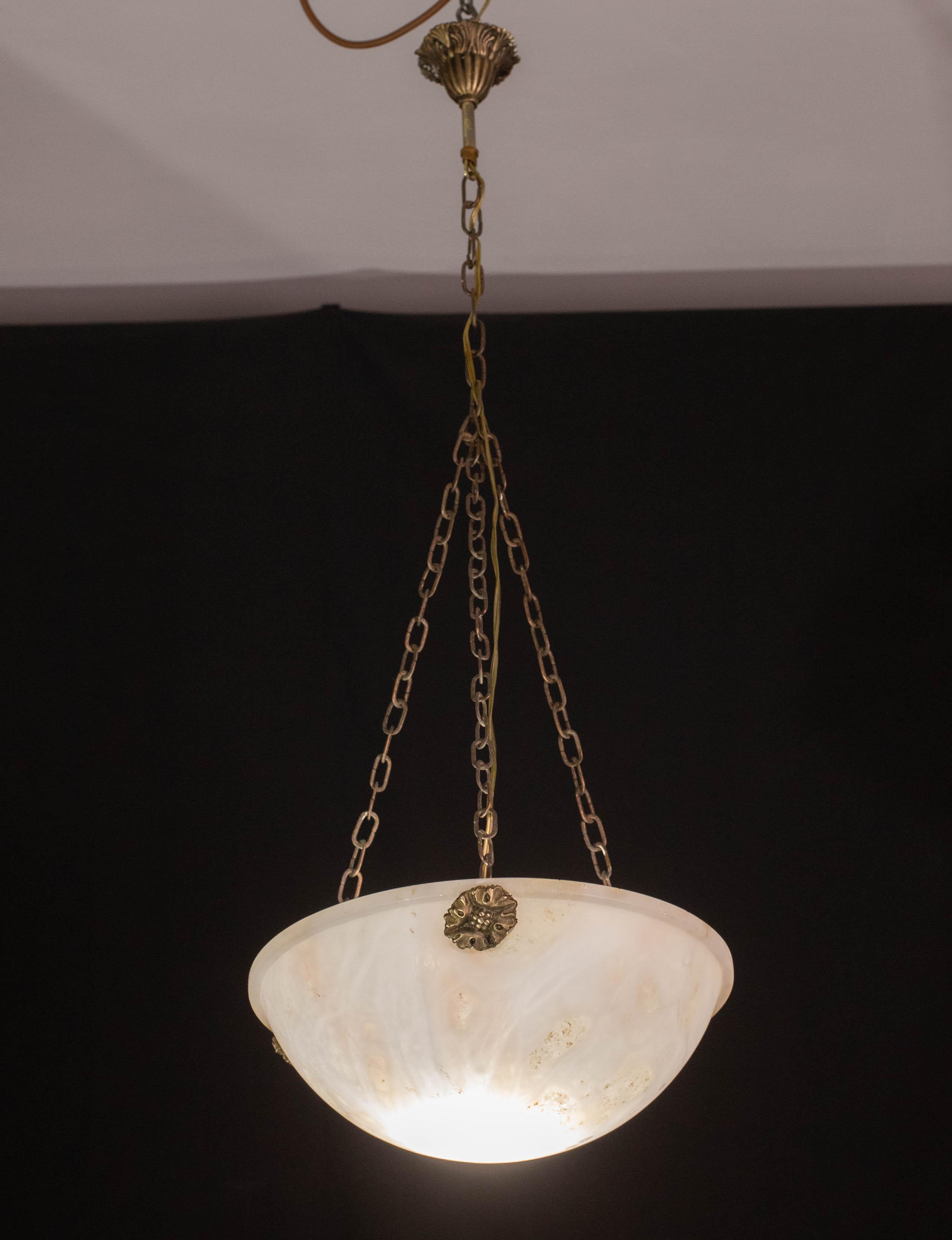 Suspension ancienne en albâtre de style Art Déco, vers les années 1940.
Une seule pièce d'albâtre, magnifiquement travaillée avec des nuances et des reflets d'autres couleurs lorsqu'elle est éclairée, suspendue à trois tiges de laiton d'origine.
La