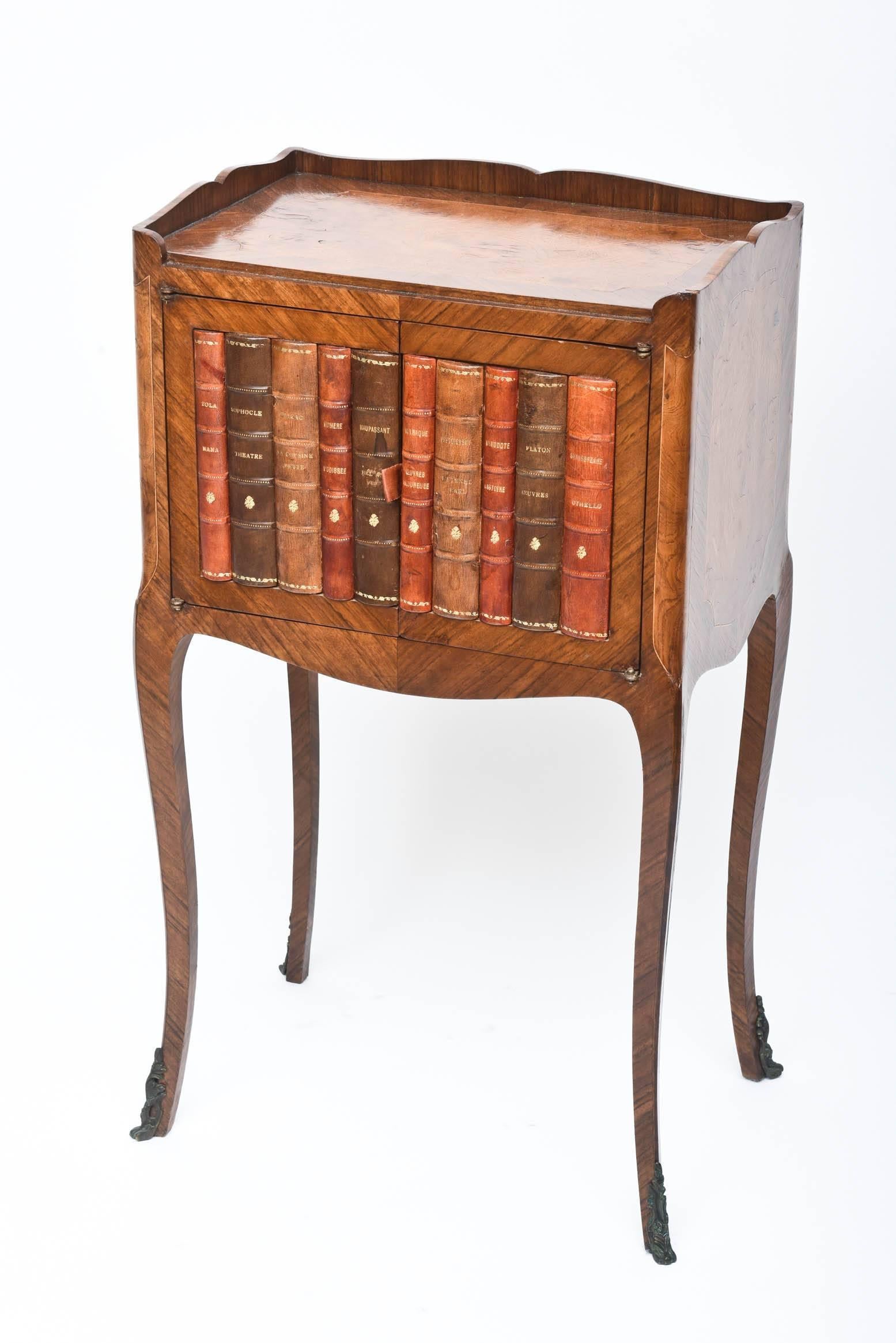 A petite table for your home office, hallway, living room featuring tooled leather book front that opens to reveal a storage area. Great stylized turned legs and wood inlaids. Very nice vintage condition.