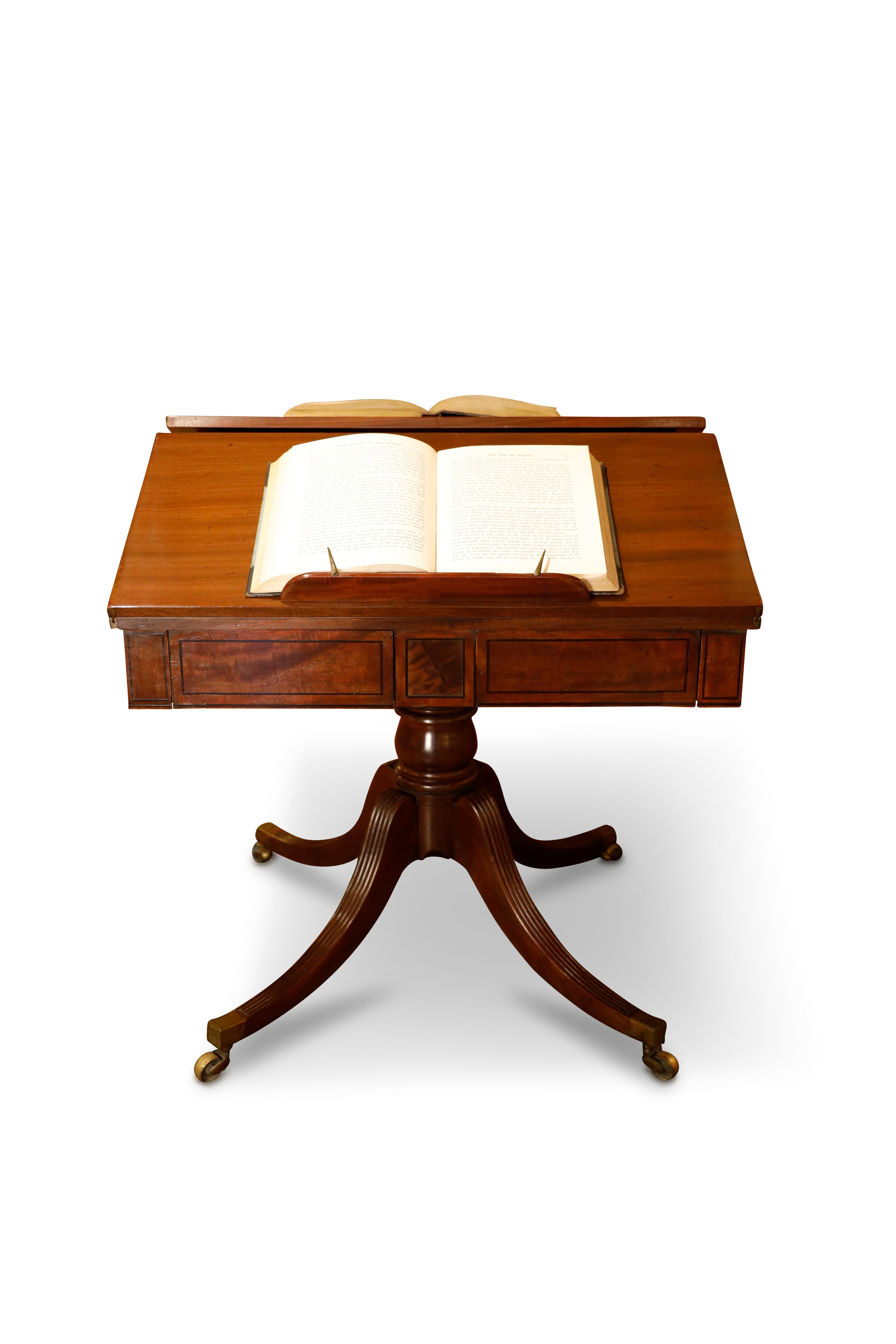 Regency mahogany library table features twin hinged, solid mahogany leaves that can either extend the top as writing surfaces or be used as book supports for reading.  Underneath the top there are opposing frieze drawers and false drawers.  The