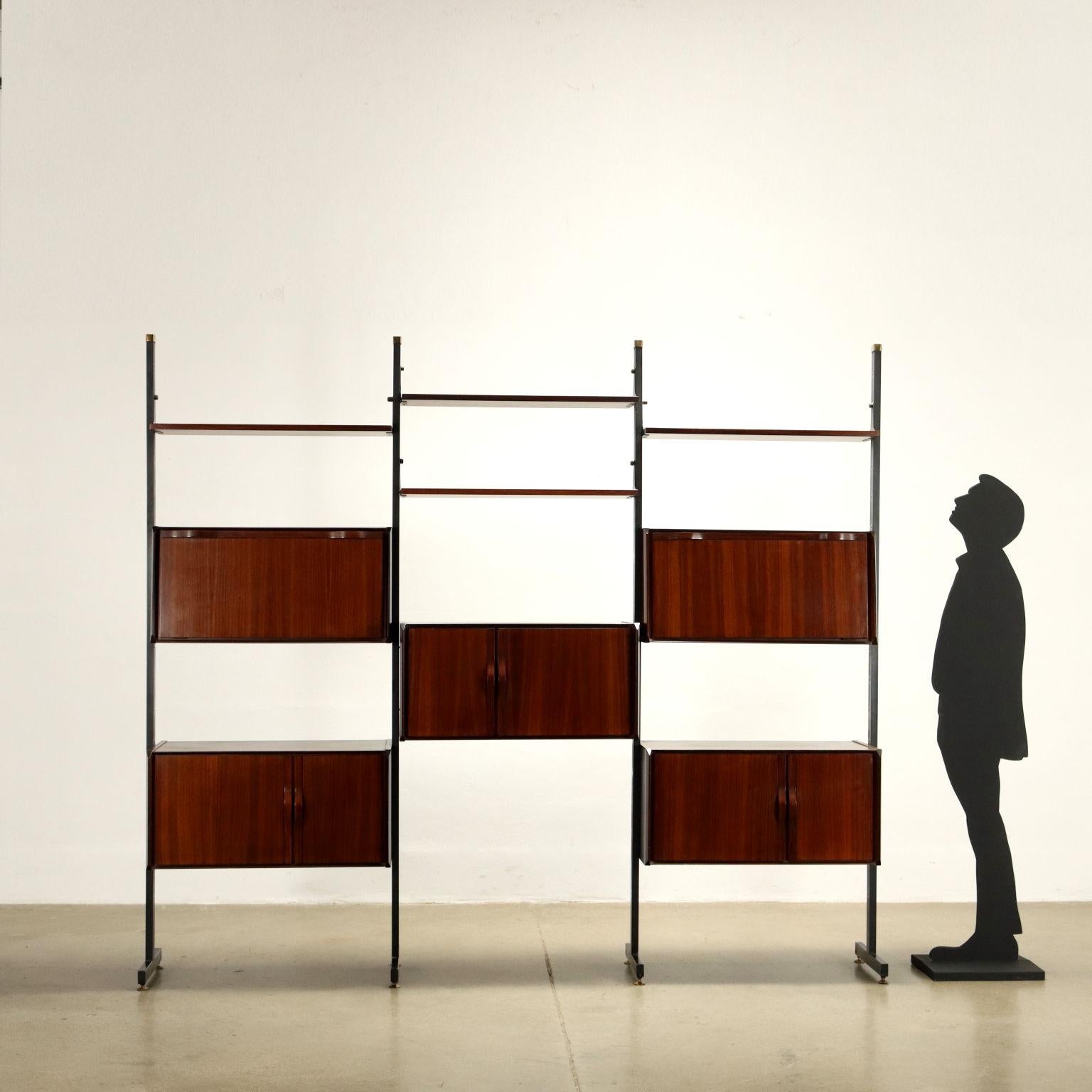 Bookcase with storage elements and open shelves, adjustable position, hinged doors and flap doors. Uprights in enameled metal, brass, exotic wood veneer. A very functional piece of furniture that can be placed along a wall, it combines storage and