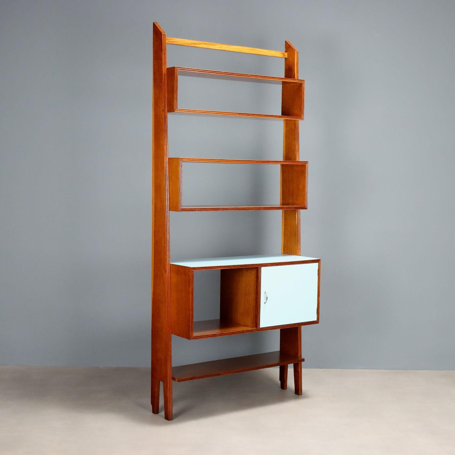 Mobile libreria vintage ad una campata in legno impiallacciato rovere con inserti in formica. Presenta vani a giorno e vano contenitore con anta battente con maniglia in ottone. Arredo restaurato nei nostri laboratori.