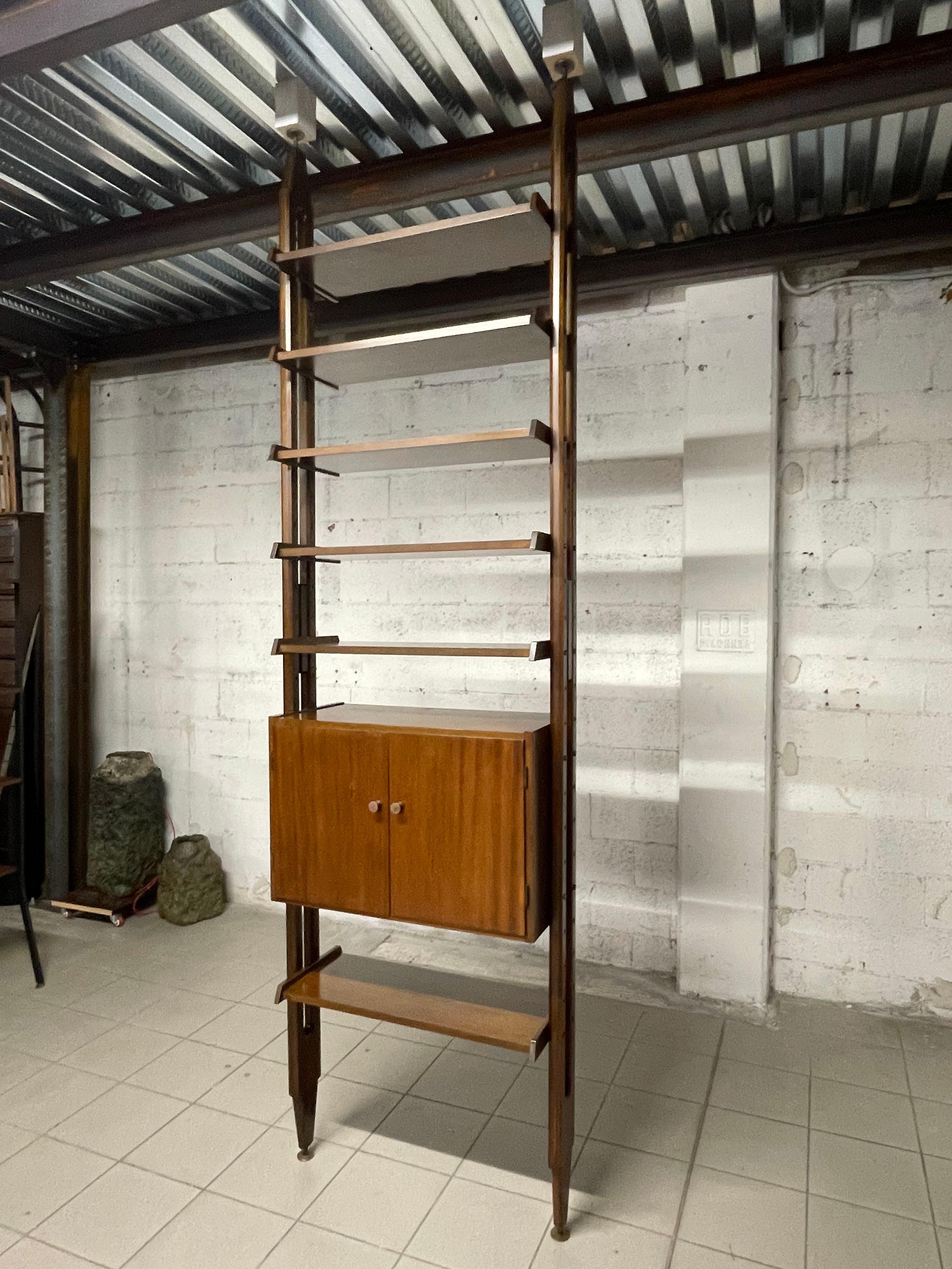 Libreria cielo-terra anni '60 a una campata in legno di teak.

La struttura della libreria è composta da 6 mensole di profondità 30 cm. e un vano chiuso con due antine.

I piedini in ottone sono regolabili per una migliore adattabilità a pavimento e