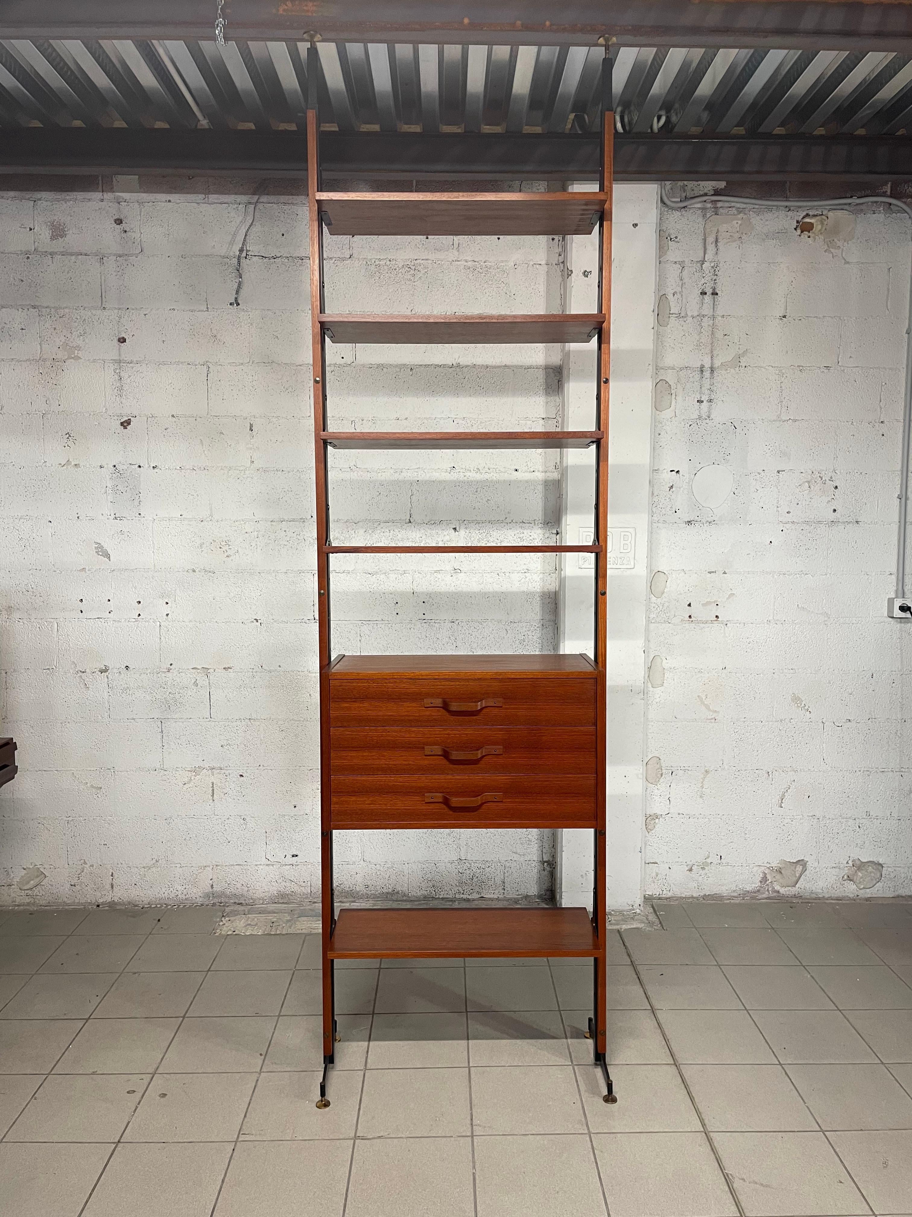 Libreria cielo-terra anni '60 in legno di teak.
La struttura portante è in legno di teak e metallo verniciato nero con piedini in ottone.
L'altezza della struttura è regolabile e va da un minimo di 270 cm 270 a una massima di 328 cm.
Quella indicata