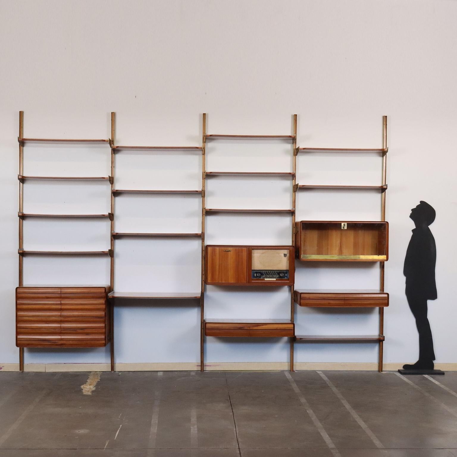 Elegante libreria a parete che necessita di ancoraggio a parete dei montanti, con elementi contenitore a cassetti e ribalta con anta in vetro, ripiani a giorno, il tutto con posizioni regolabili. Legno impiallacciato ciliegio, supporti e lamine