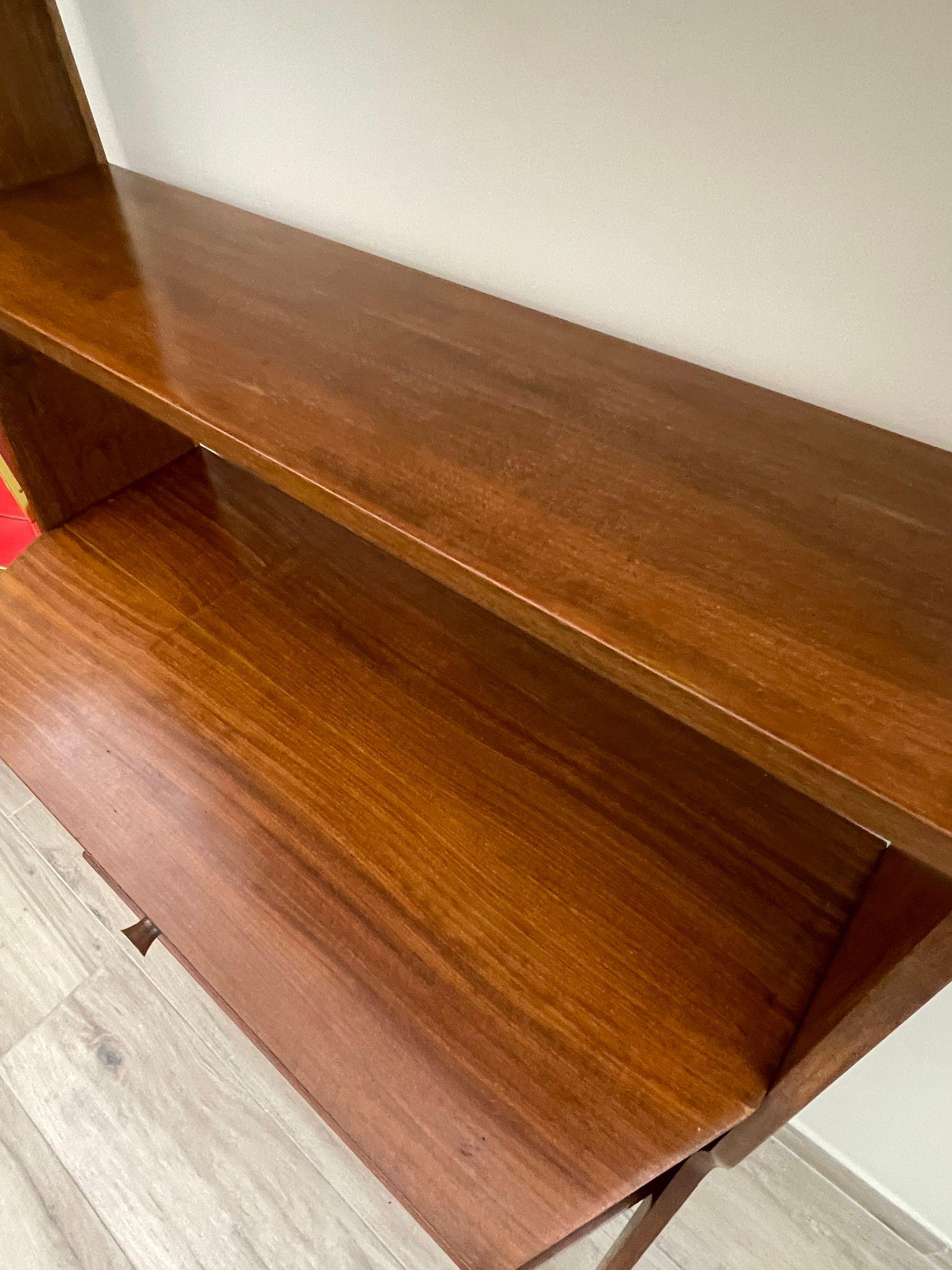 Libreria a una campata con mensole e mobiletto con anta a ribalta, anni '60.
Il design di questa libreria in legno di teak ricorda lo stile di Enzo Strada. I montanti dalla linea geometrica creano un bel movimento a tutto l'arredo.

Il frontale del