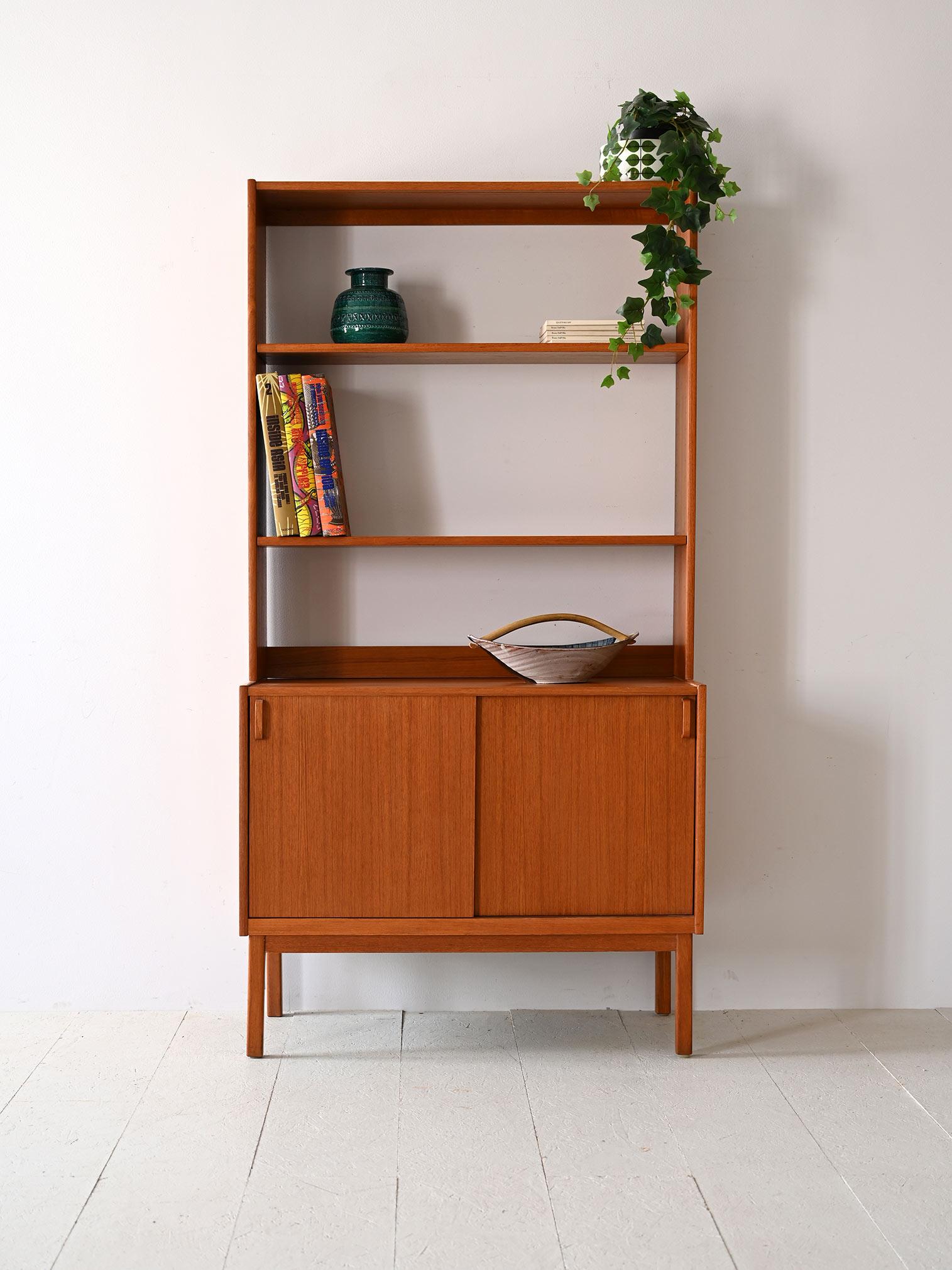 Scandinavian furniture from the 1960s that combines elegance and practicality. 
The warmth of the teak frame blends with a design that prioritizes usability: open shelves for books and art objects above a closed container to hide what you prefer to