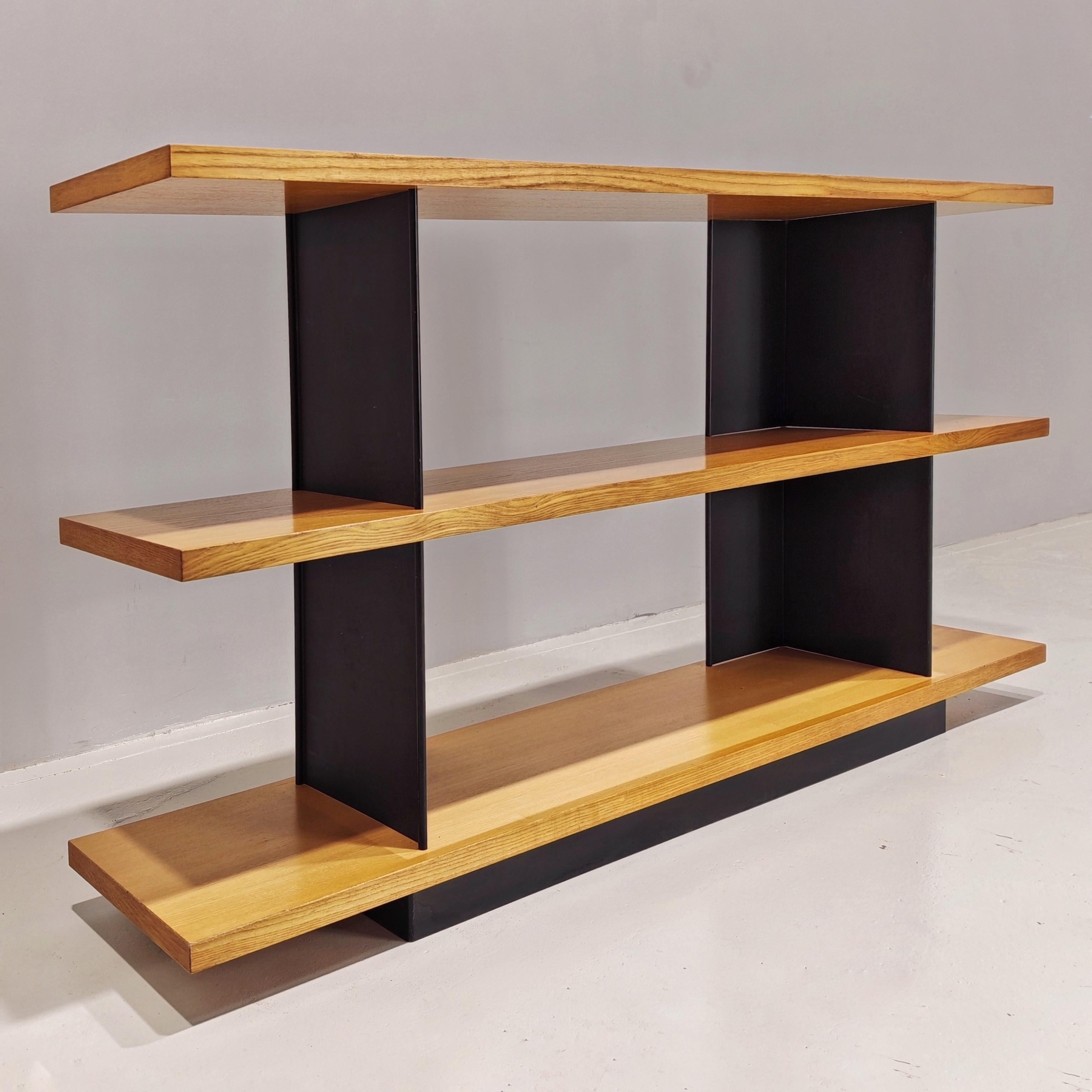 Bibliothèque des années 1970 attribuée à Charlotte Perriand, composée de grandes étagères en chêne de 160 cm de long reposant sur des coins en métal noir. 
La hauteur de 85 cm et la forme particulière de cette version rare lui permettent de