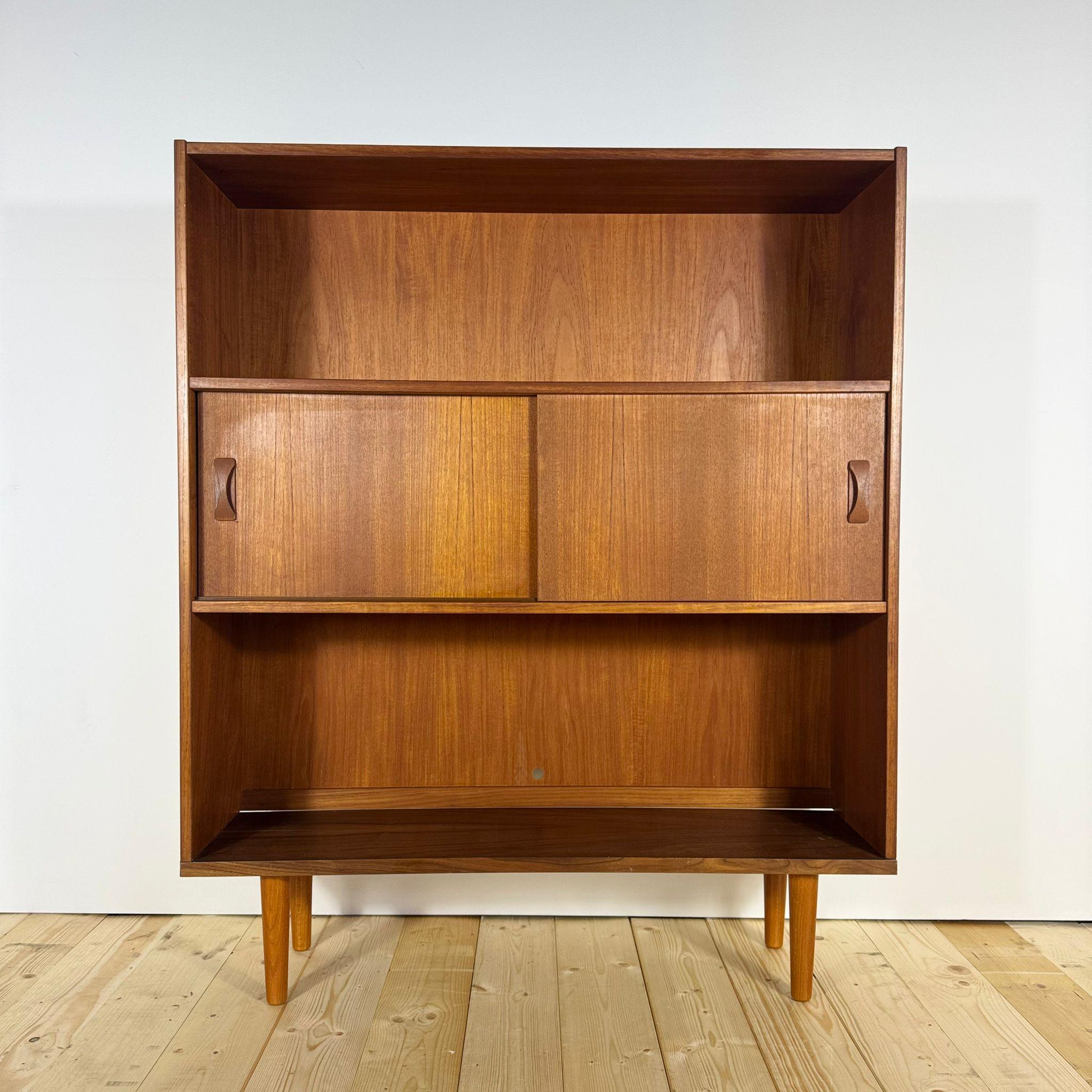 Questa libreria danese degli anni Sessanta rappresenta perfettamente l'eleganza sobria e funzionale del design Mid-Century scandinavo. Realizzato in teak impiallacciato, sfoggia una tonalità calda e uniforme che mette in risalto le venature naturali