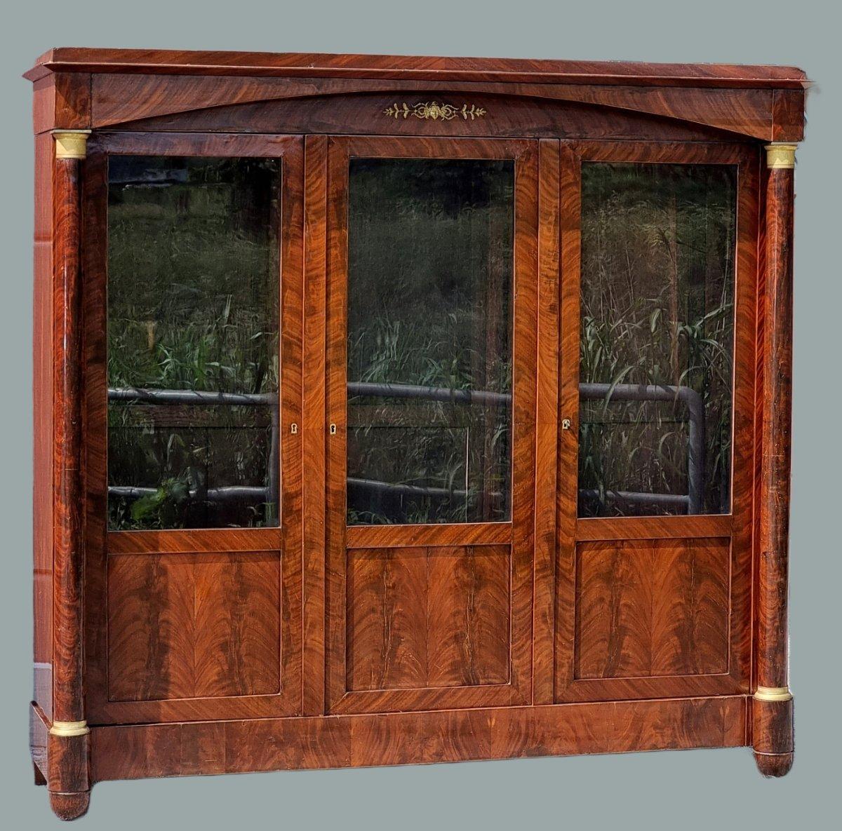 Elegante e imponente libreria francese risalente al primo periodo Impero, dei primi anni del XIX secolo. Il mobile si presenta con struttura smontabile e tripartita, con tre ante scandite da colonne tornite in legno massello, arricchite da raffinati