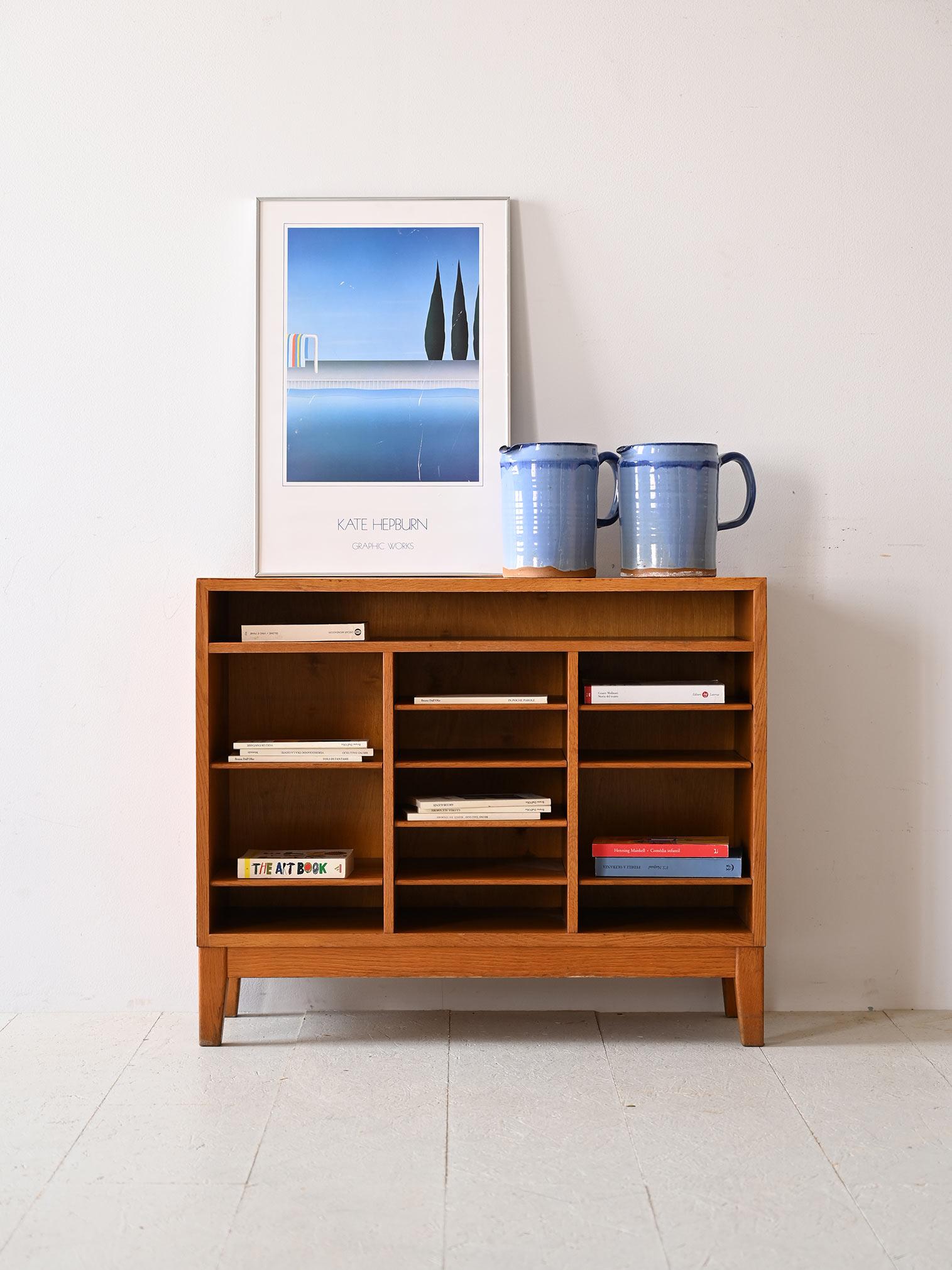 Particular Scandinavian bookcase made of oak wood.

The linearly designed structure shows open shelving units varying in height and size. This multiplicity of shelves offers a variety of display options for books and objects. 
The light wood frame